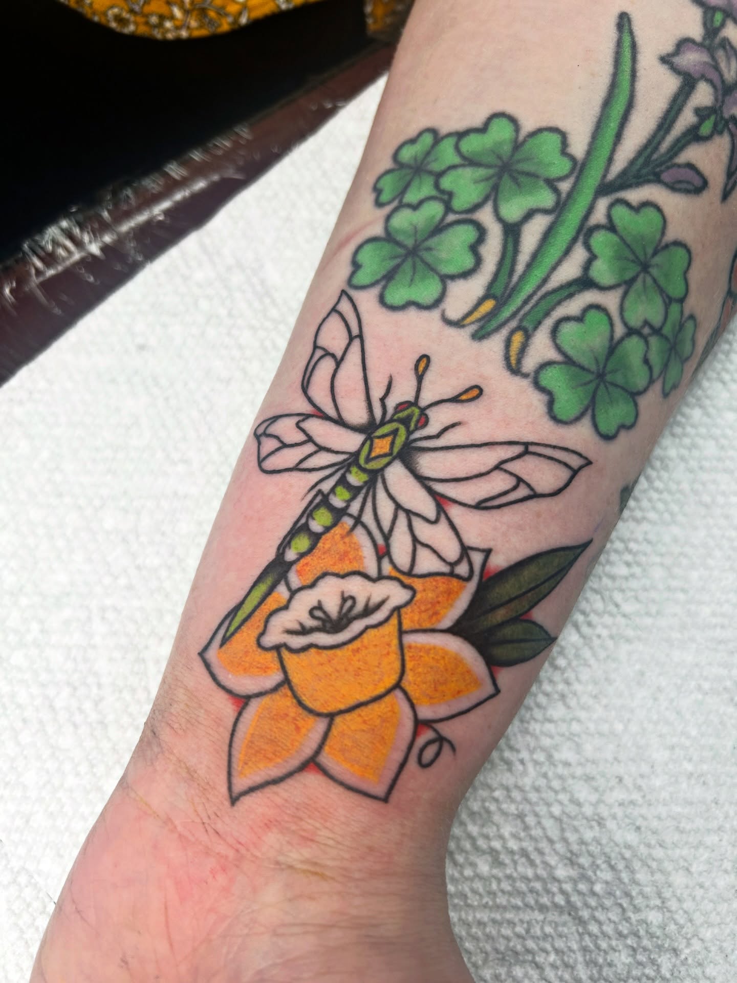 Daffodil and dragonfly American traditional tattoo on the forearm by Dylan James
