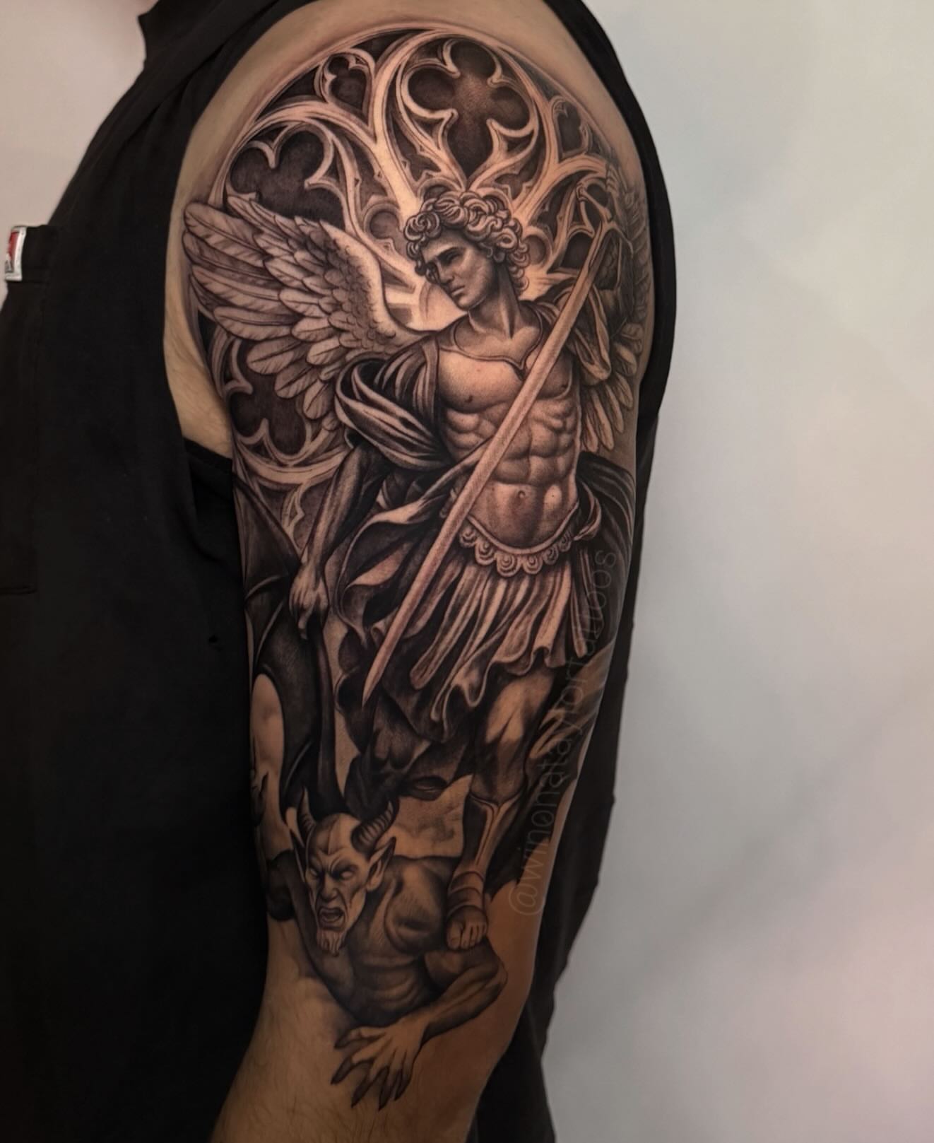 Angel slaying demon realism tattoo on the upper arm by 𝒲𝒾𝓃𝑜𝓃𝒶