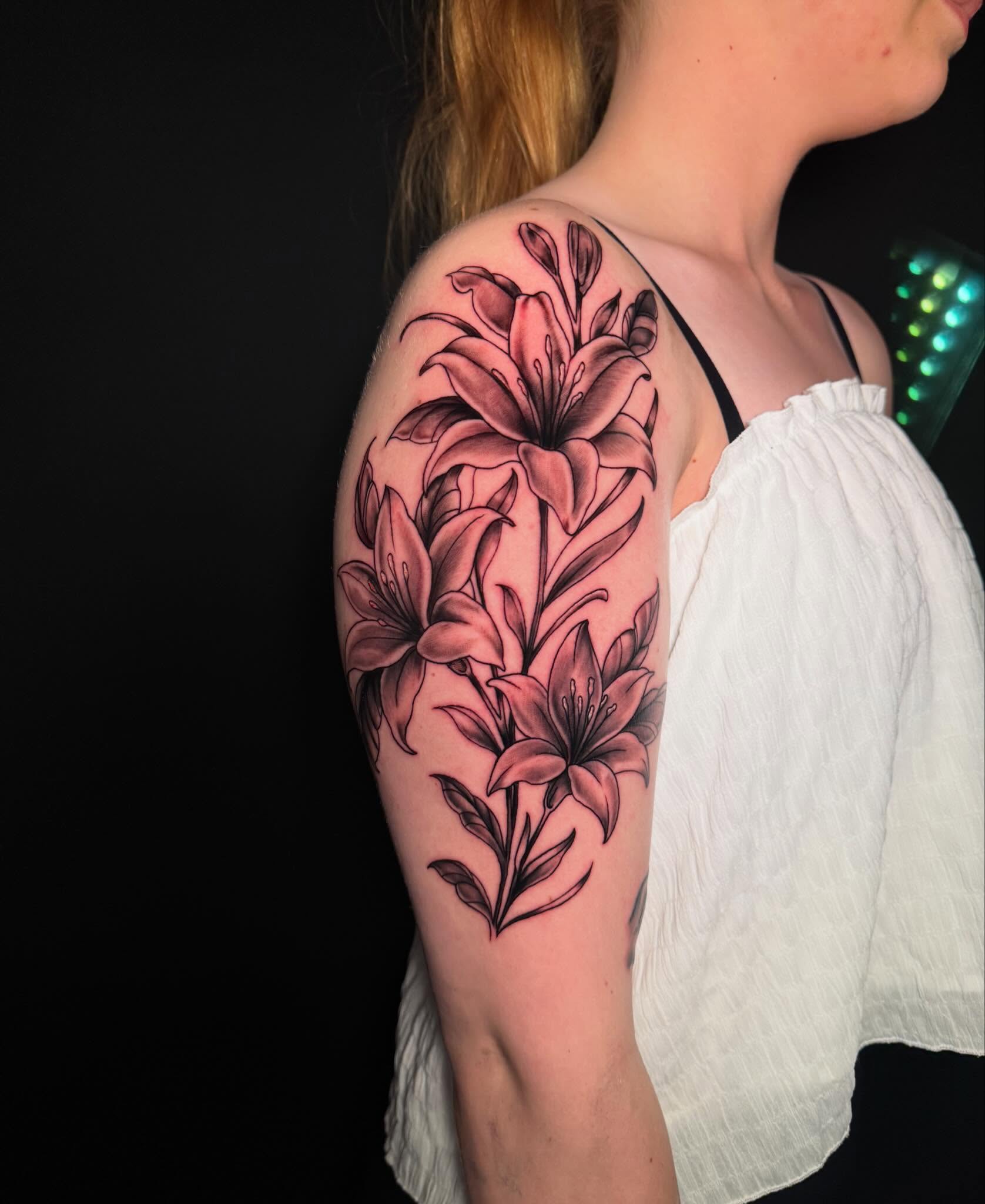 Lilies black and grey tattoo on the upper arm by Jewels, St. George, Utah