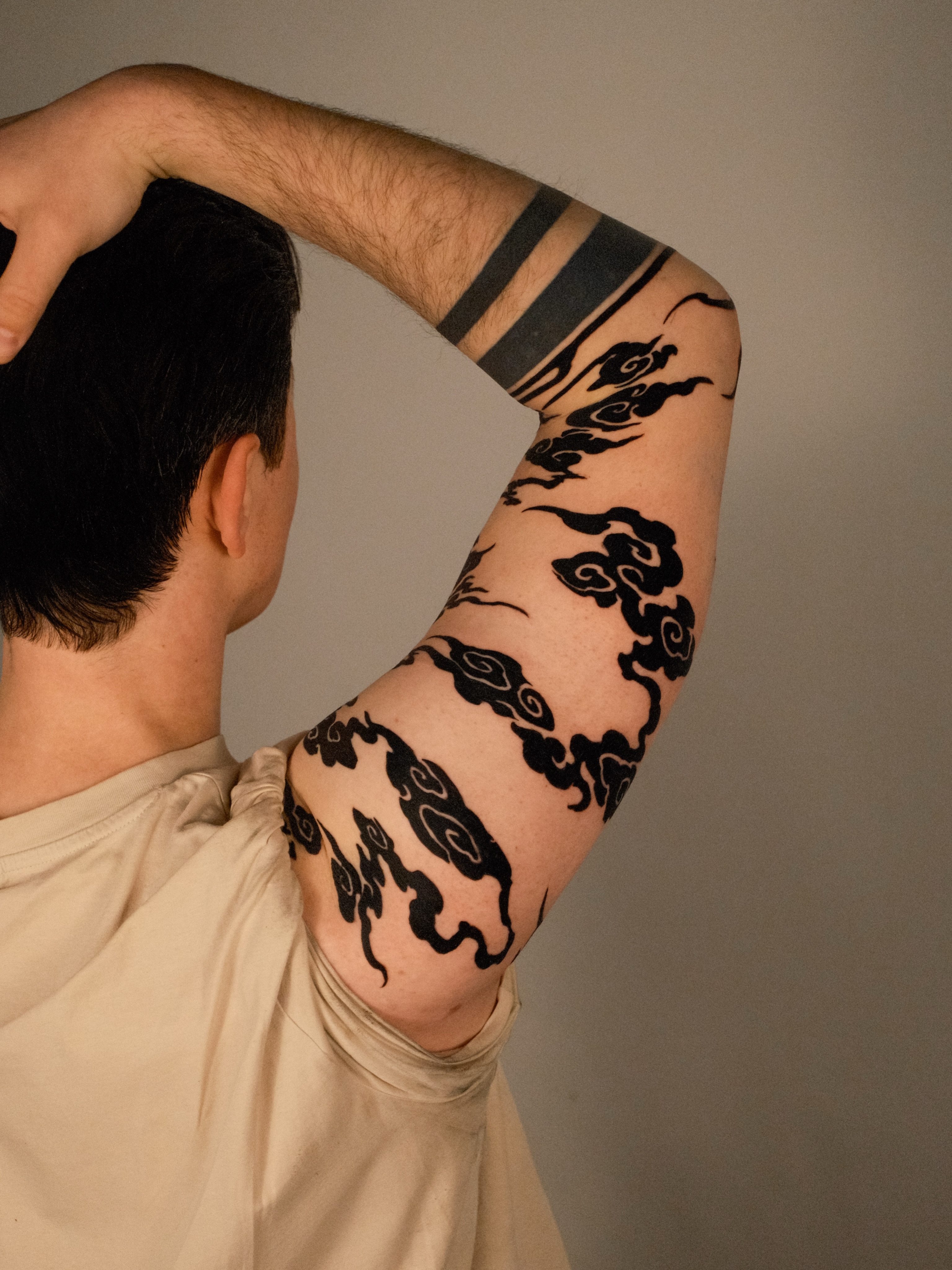 Clouds black and grey tattoo on the upper arm by Kubo