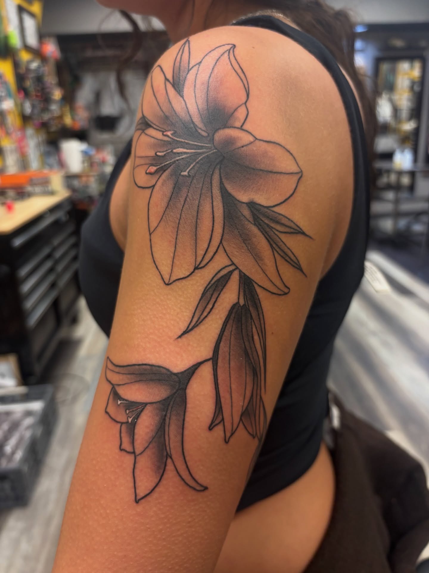 Lily black and grey tattoo on the upper arm by Megan
