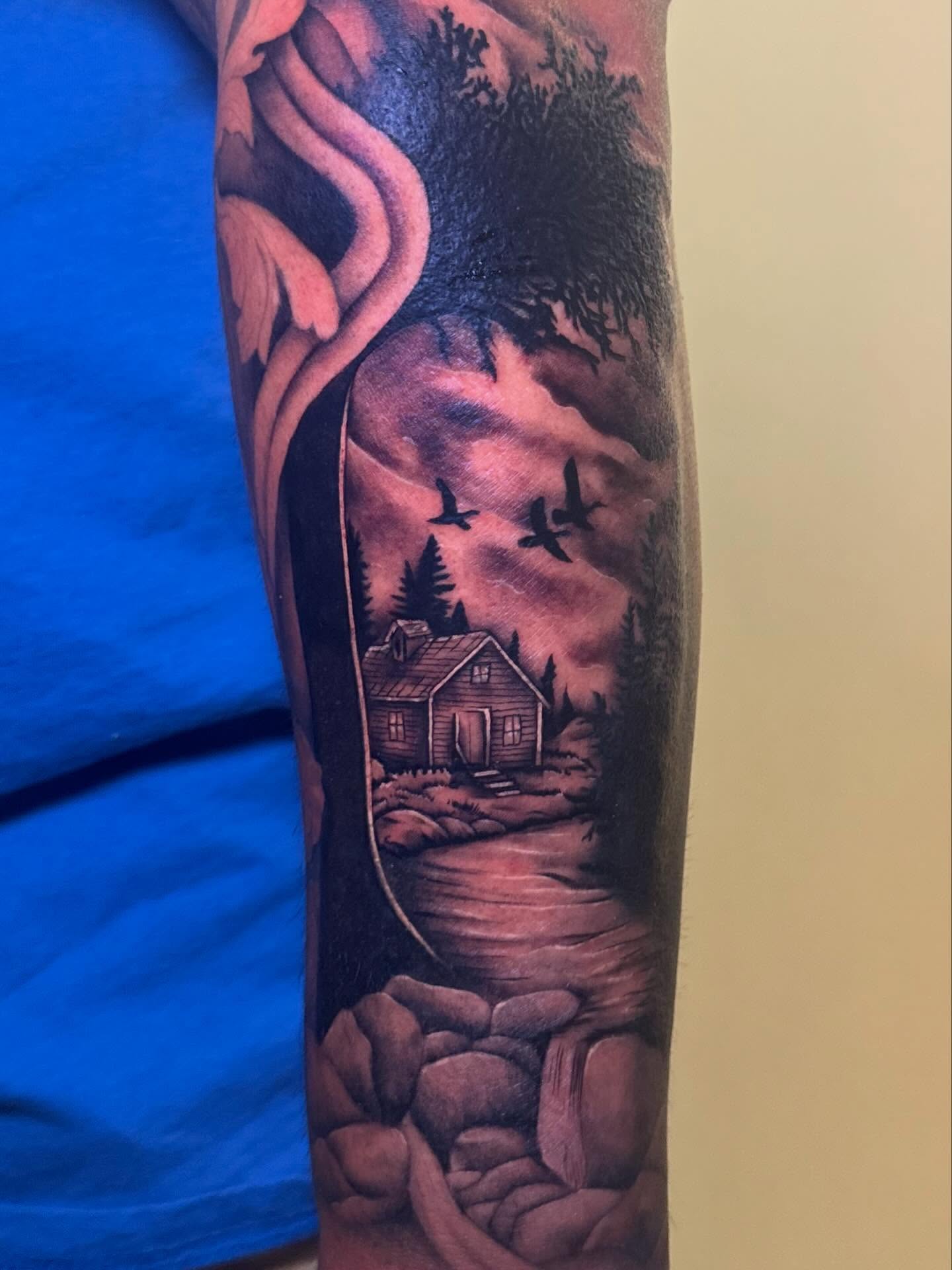 House in forest realism tattoo on the forearm by Madison Pegram