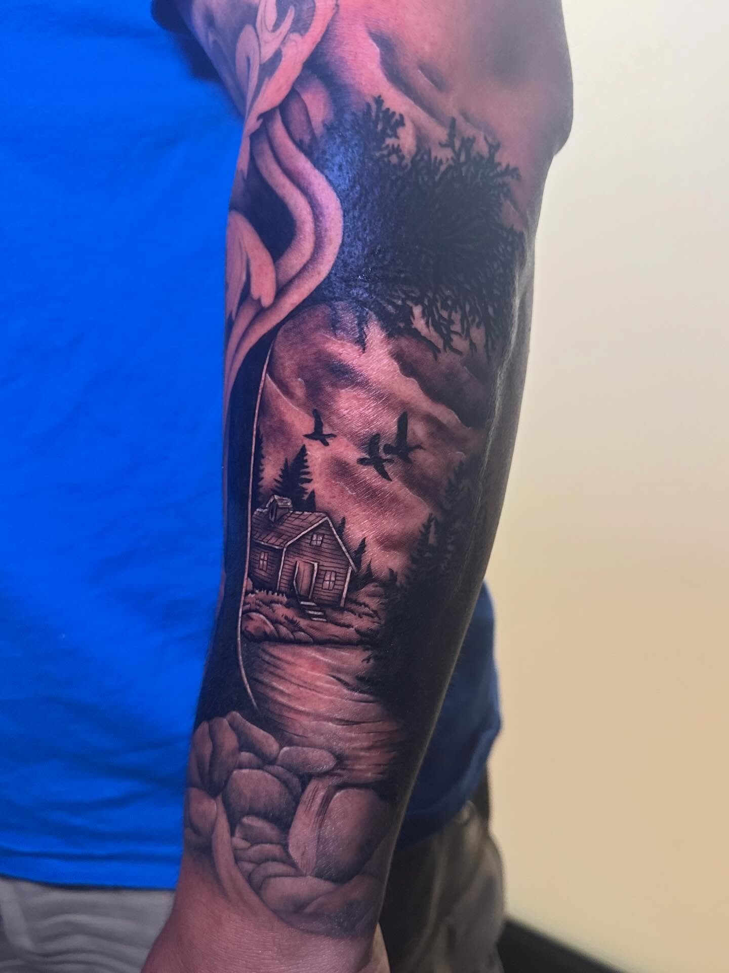 House and landscape realism tattoo on the forearm by Madison Pegram