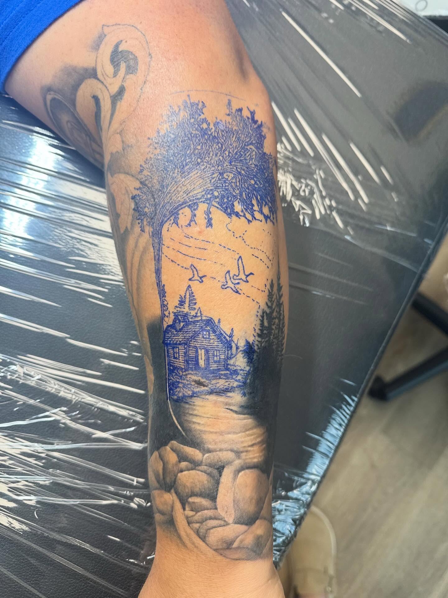 Rustic cabin landscape realism tattoo on the forearm by Madison Pegram
