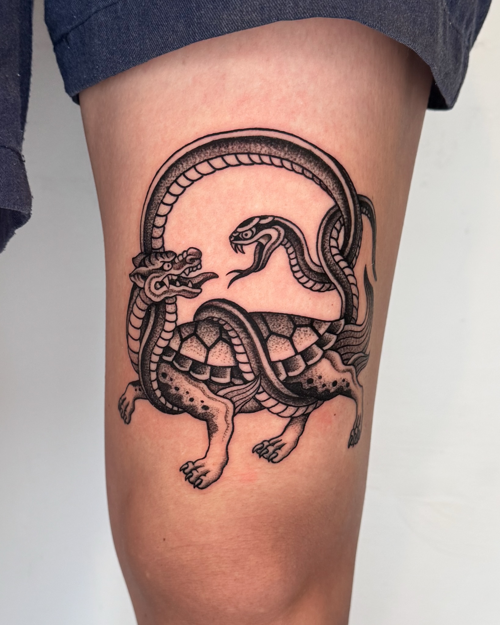 Serpent and turtle black and grey tattoo on the thigh by Jae Traditional Tattoo