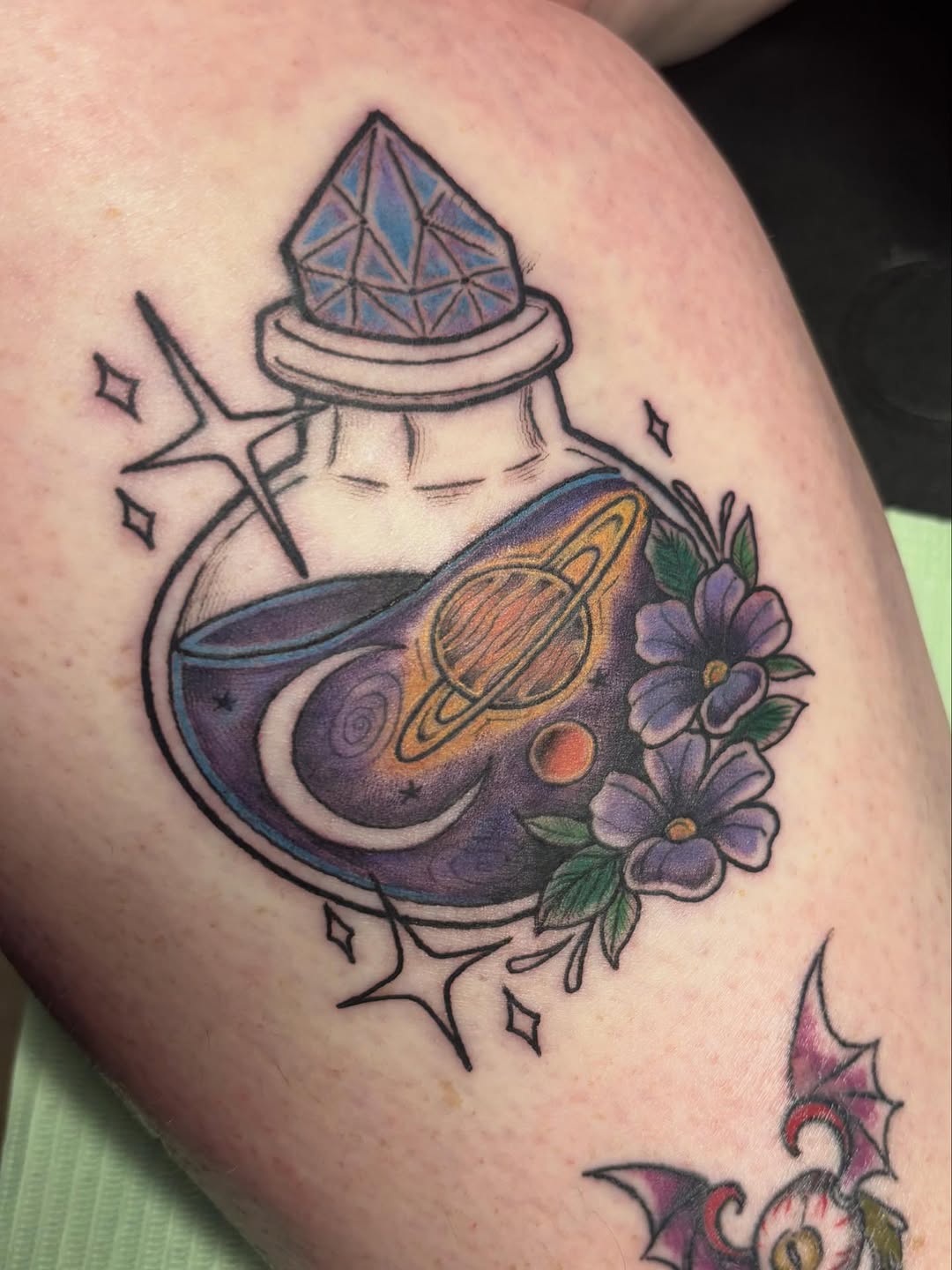 Potion bottle with galaxy and flowers minimalist tattoo on the thigh by Christhian King