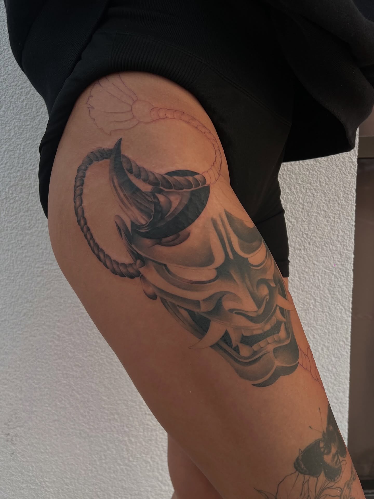 Mask and rope black and grey tattoo on the thigh by Espi