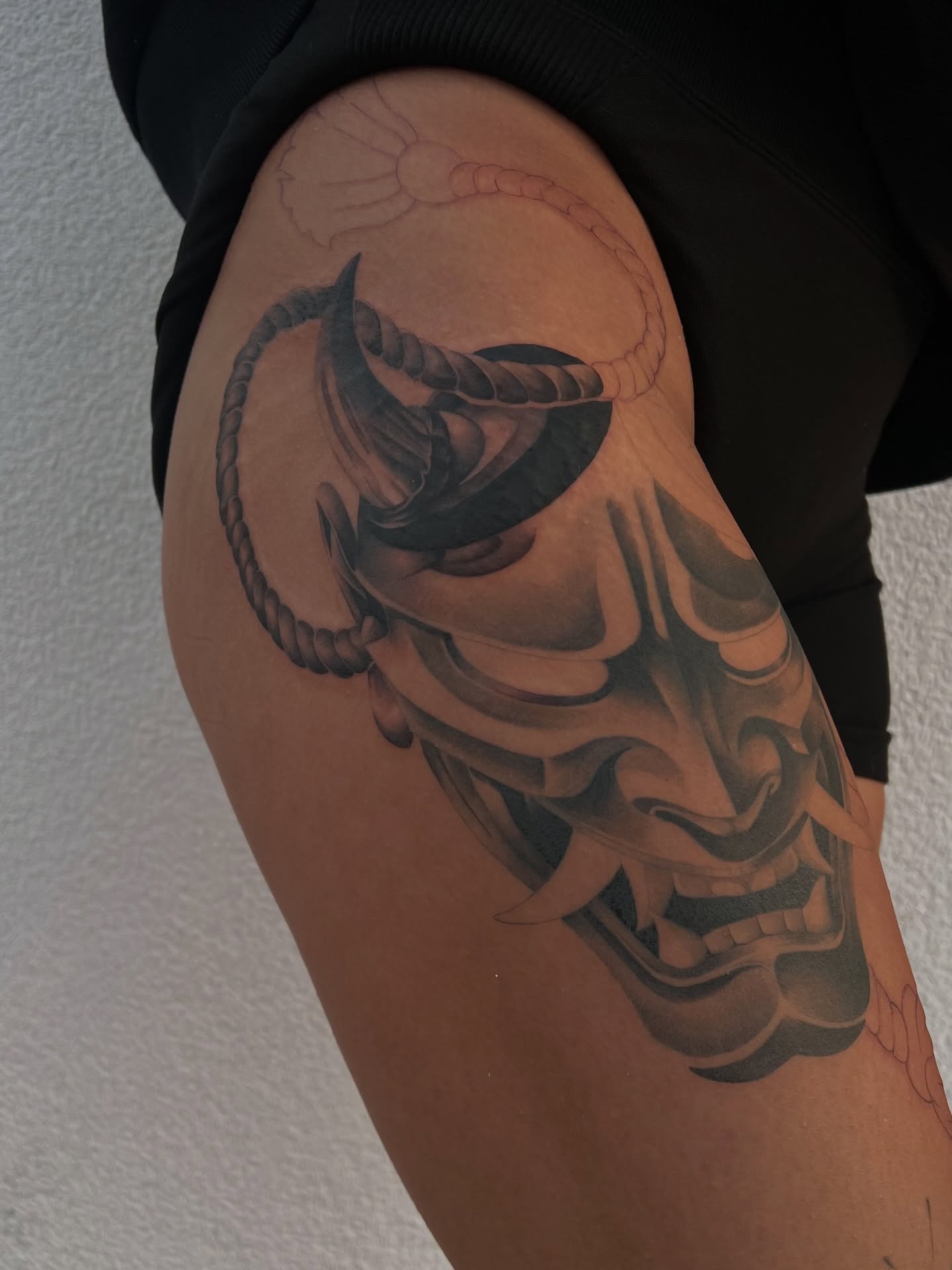 Mask black and grey tattoo on the thigh by Espi