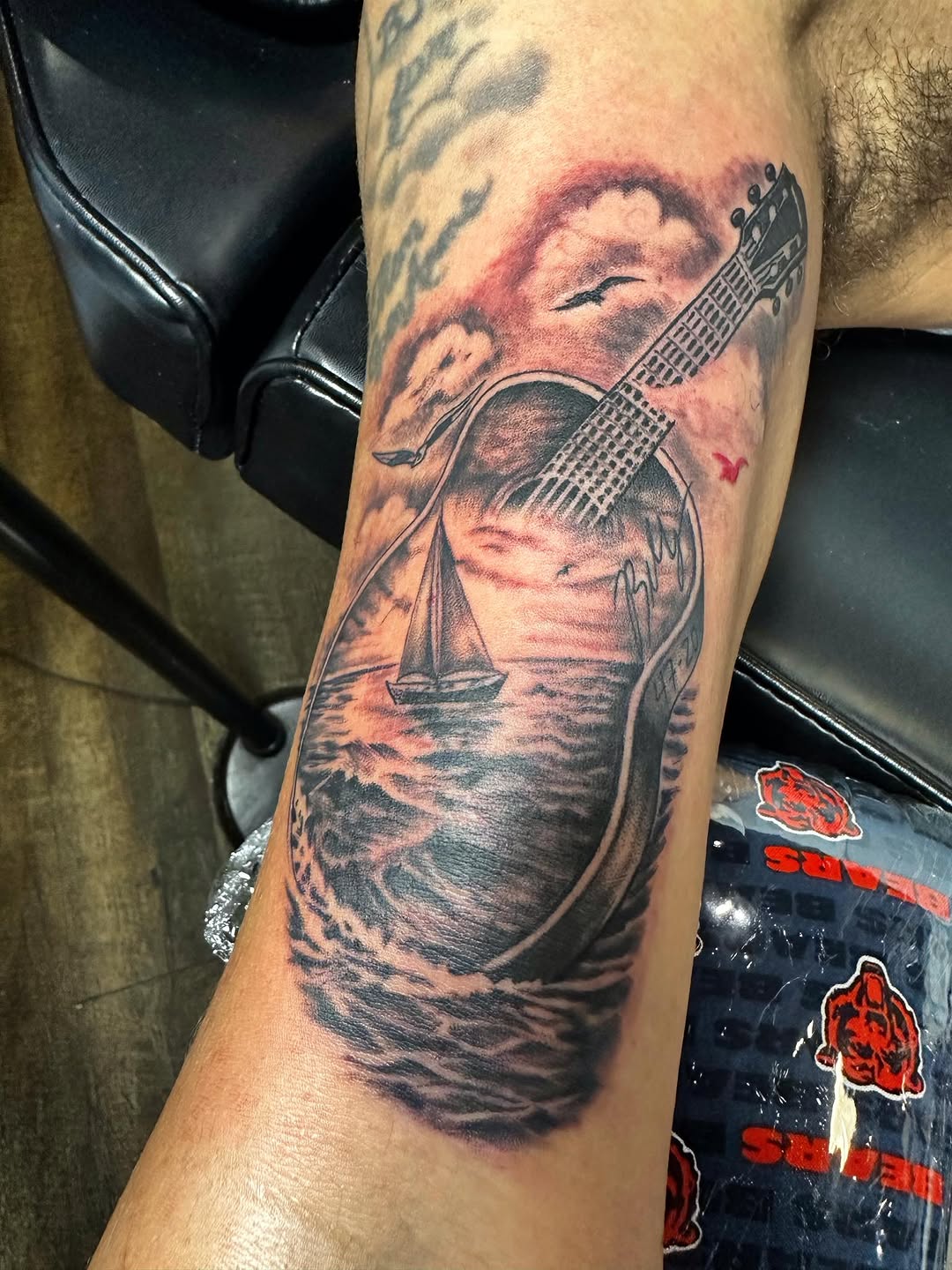 Guitar with seascape tattoo on the forearm by Jason Ponce