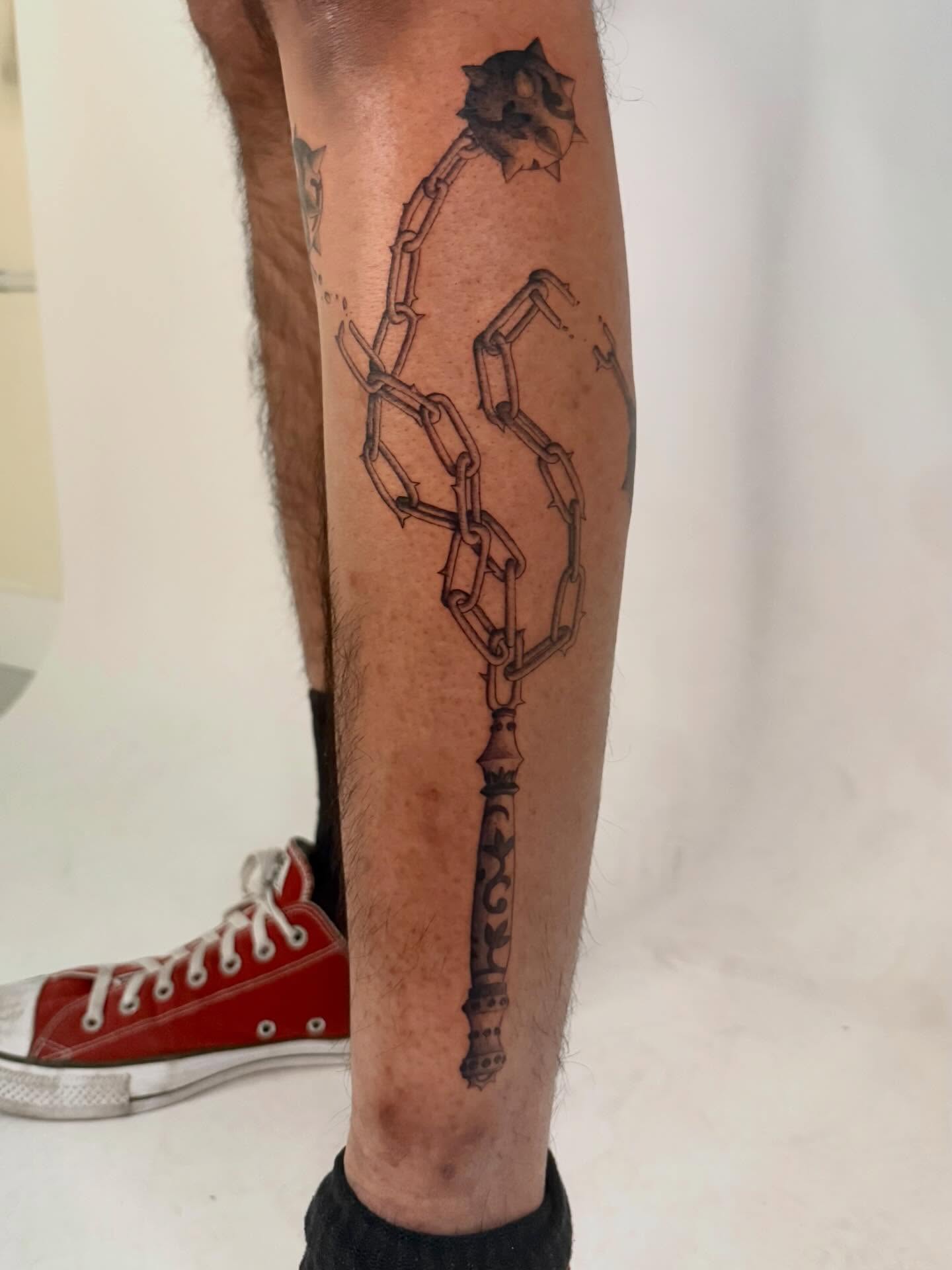 Key and chain black and grey tattoo on the calf by Andrew Flatts