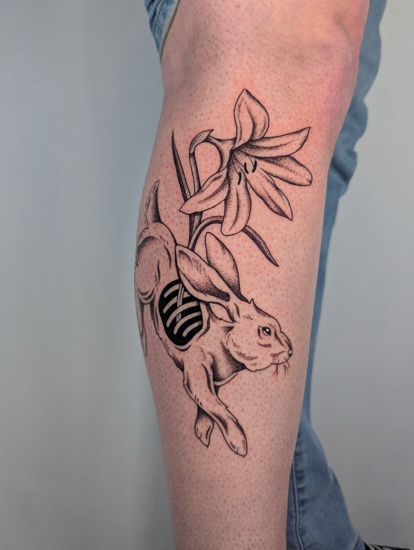 Rabbit and lily dotwork tattoo on the forearm by Courtney Yaddof