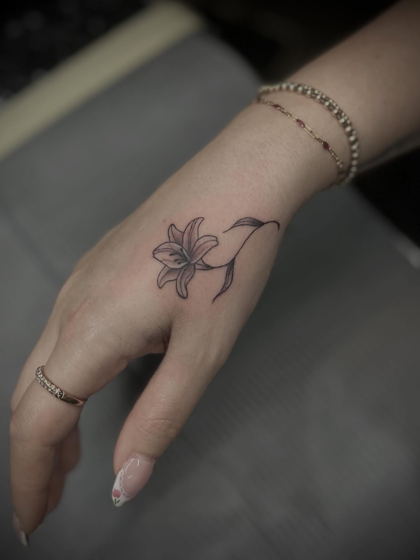 Lily black and grey tattoo on the hand by Lexi Rose