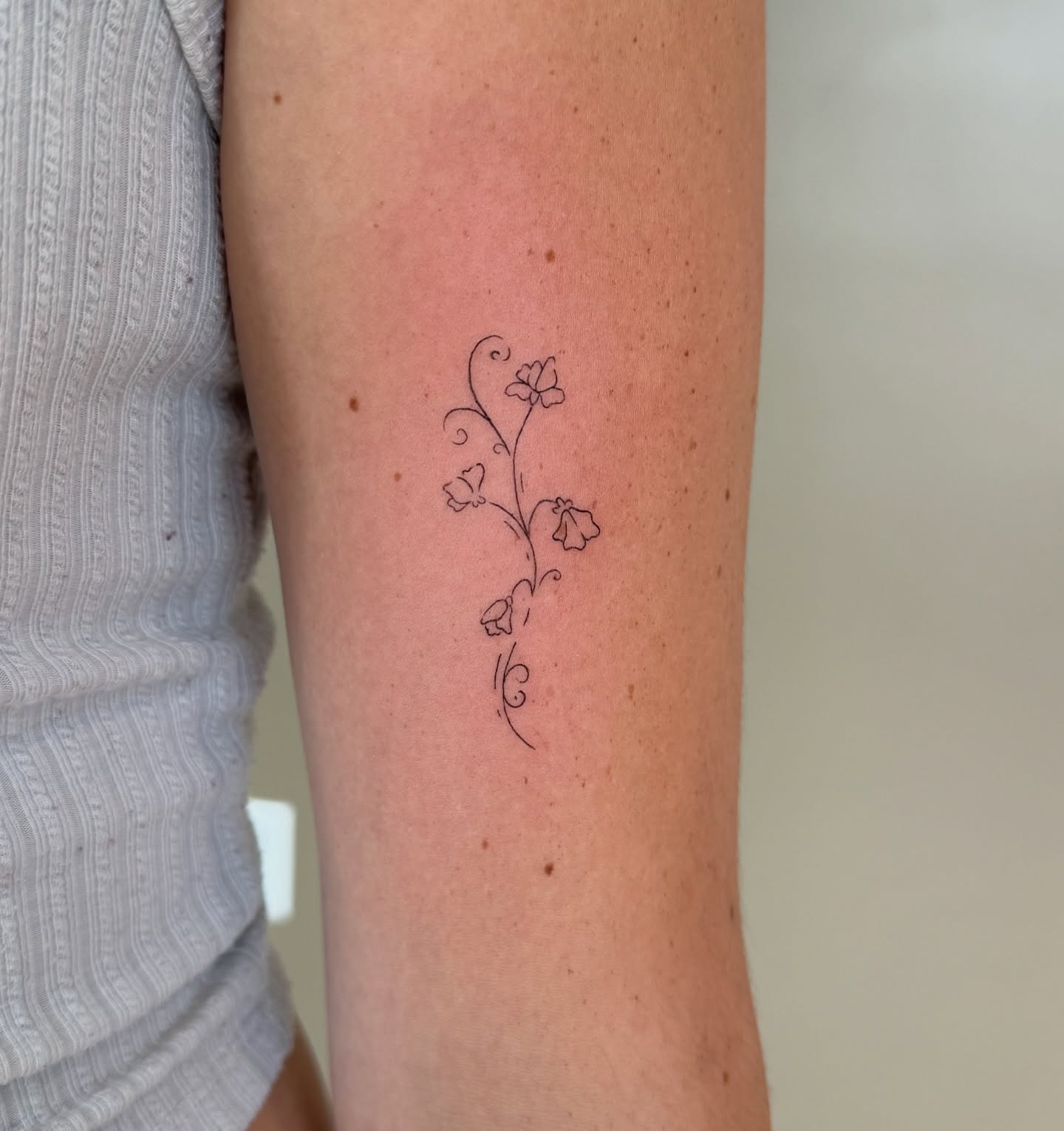 Floral vine fine line tattoo on the forearm by Fine Line Tattoos