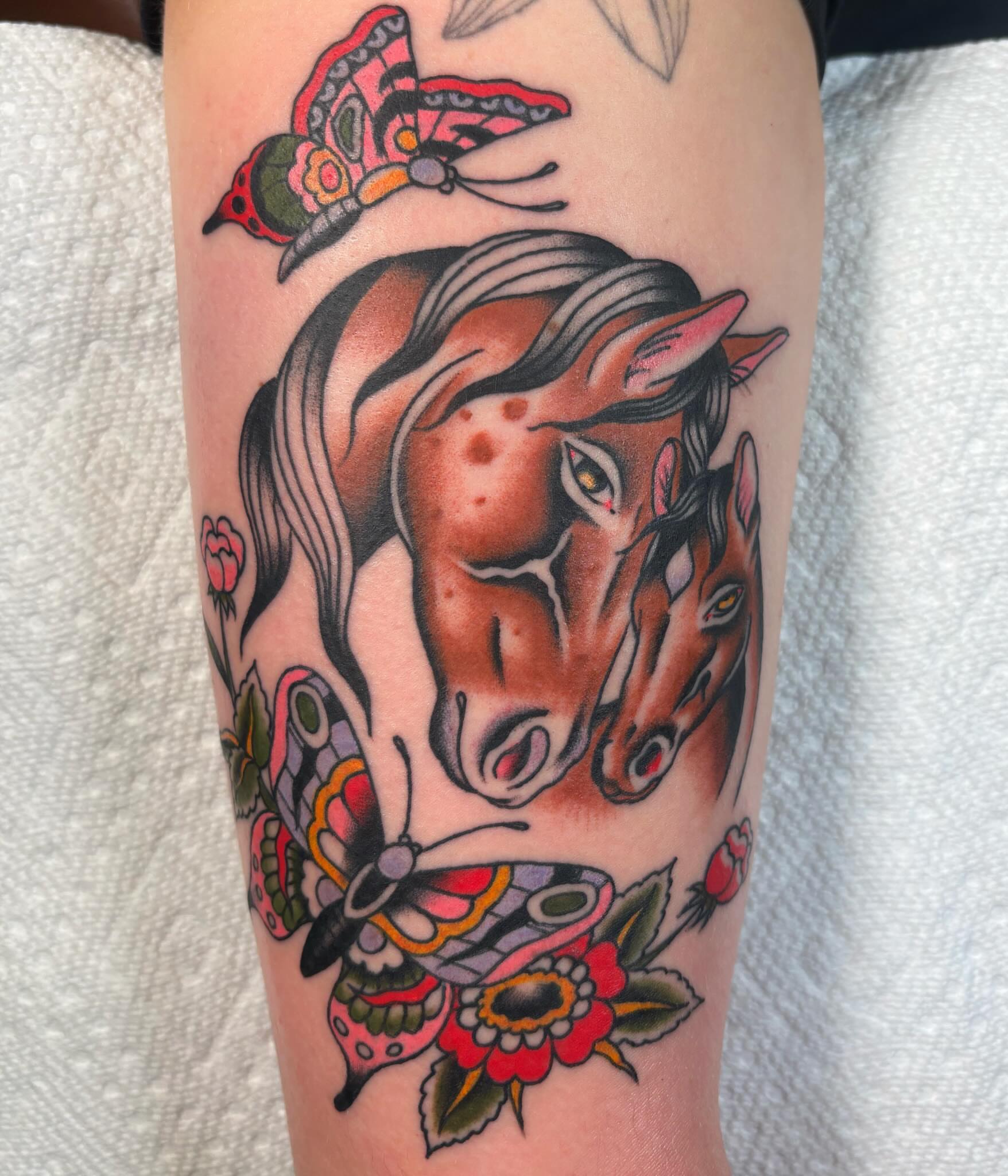 Horses and butterflies American traditional tattoo on the forearm by Caeli Martin