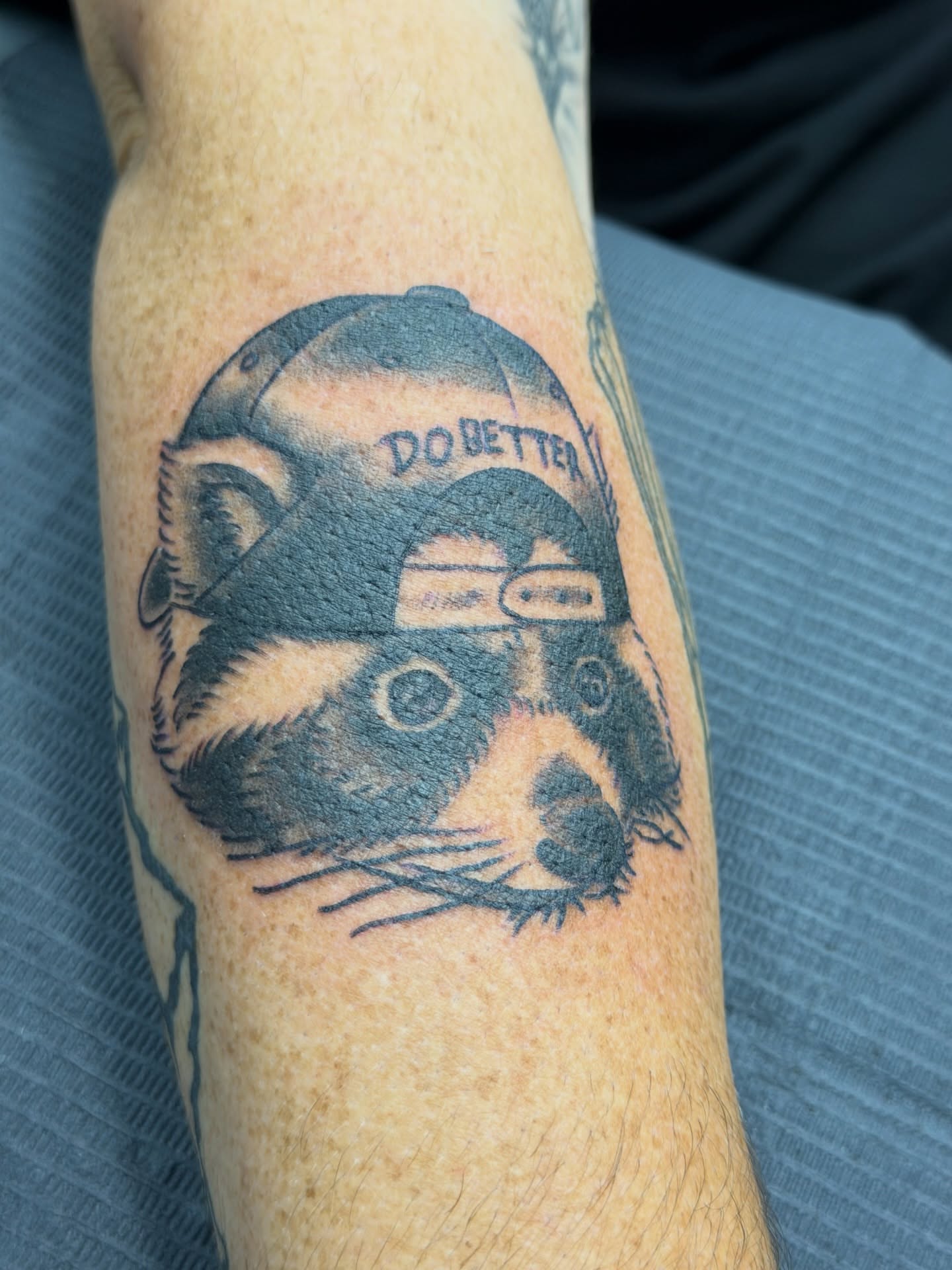 Otter wearing cap black and grey tattoo on the forearm by Squid