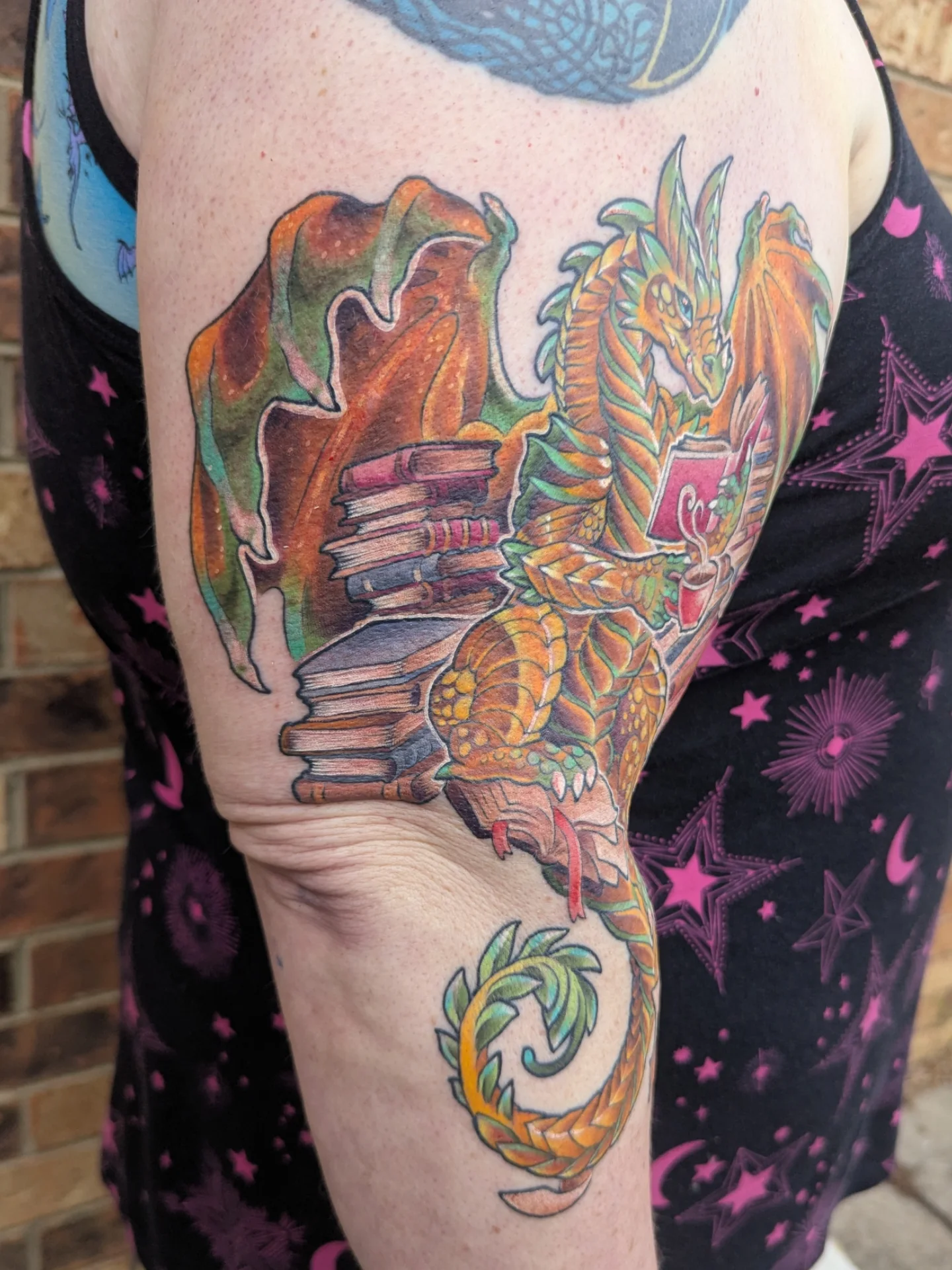 Dragon and books watercolor tattoo on the thigh by Devon Greig