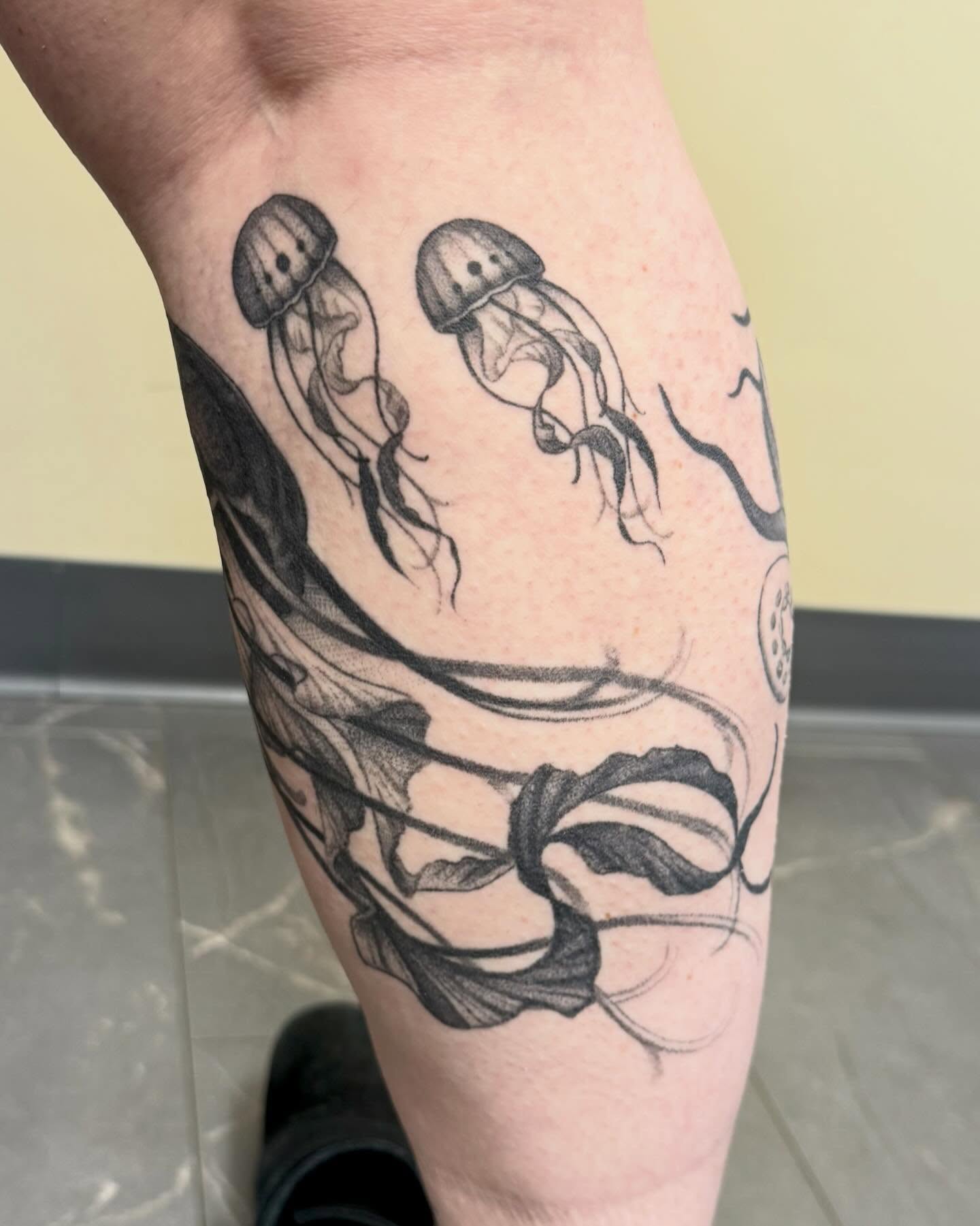 Jellyfish and seaweed realism tattoo on the calf by jada