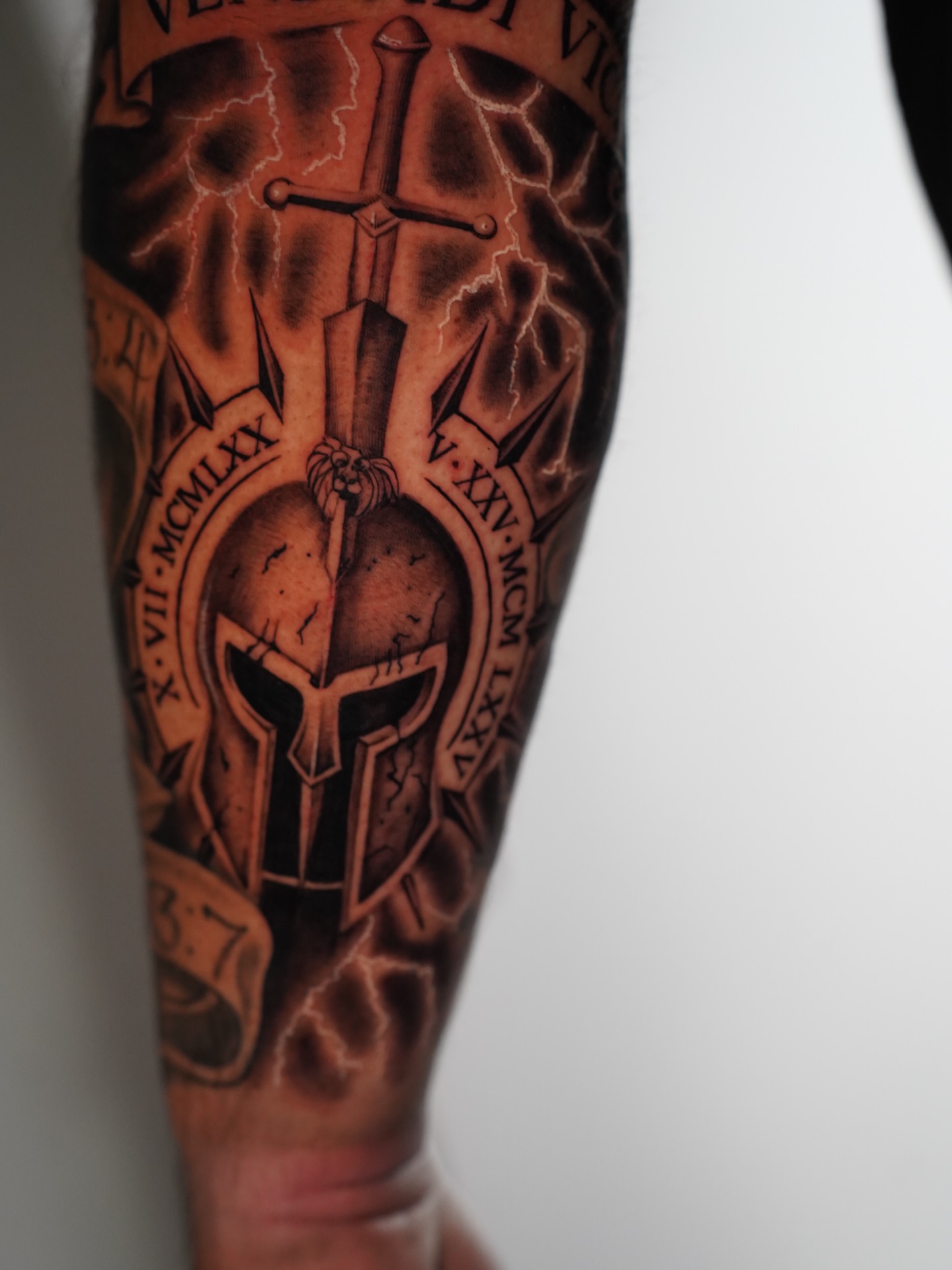 Spartan helmet and sword black and grey tattoo on the forearm by Dallas Tattoo Artist