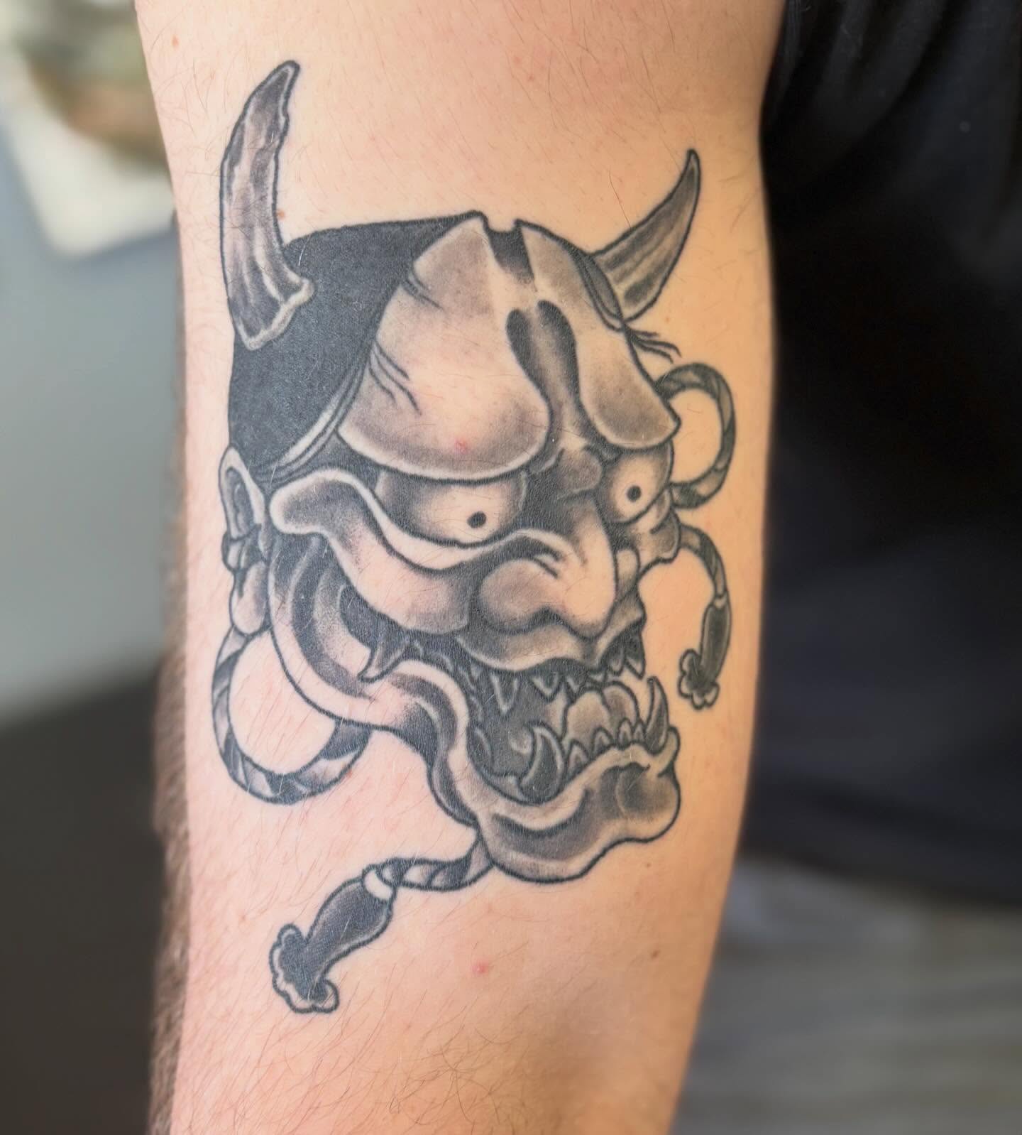 Demon mask black and grey tattoo on the forearm by Gabby, Kansas City, Missouri
