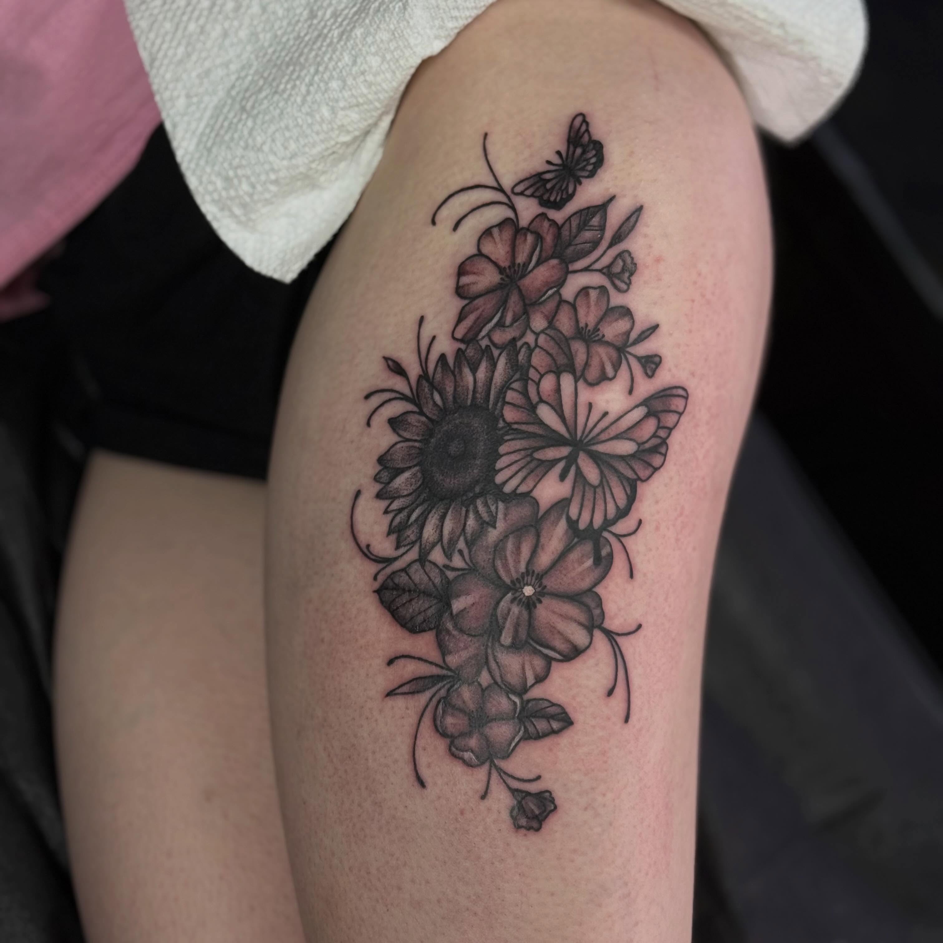 Flower bouquet black and grey tattoo on the thigh by Nic