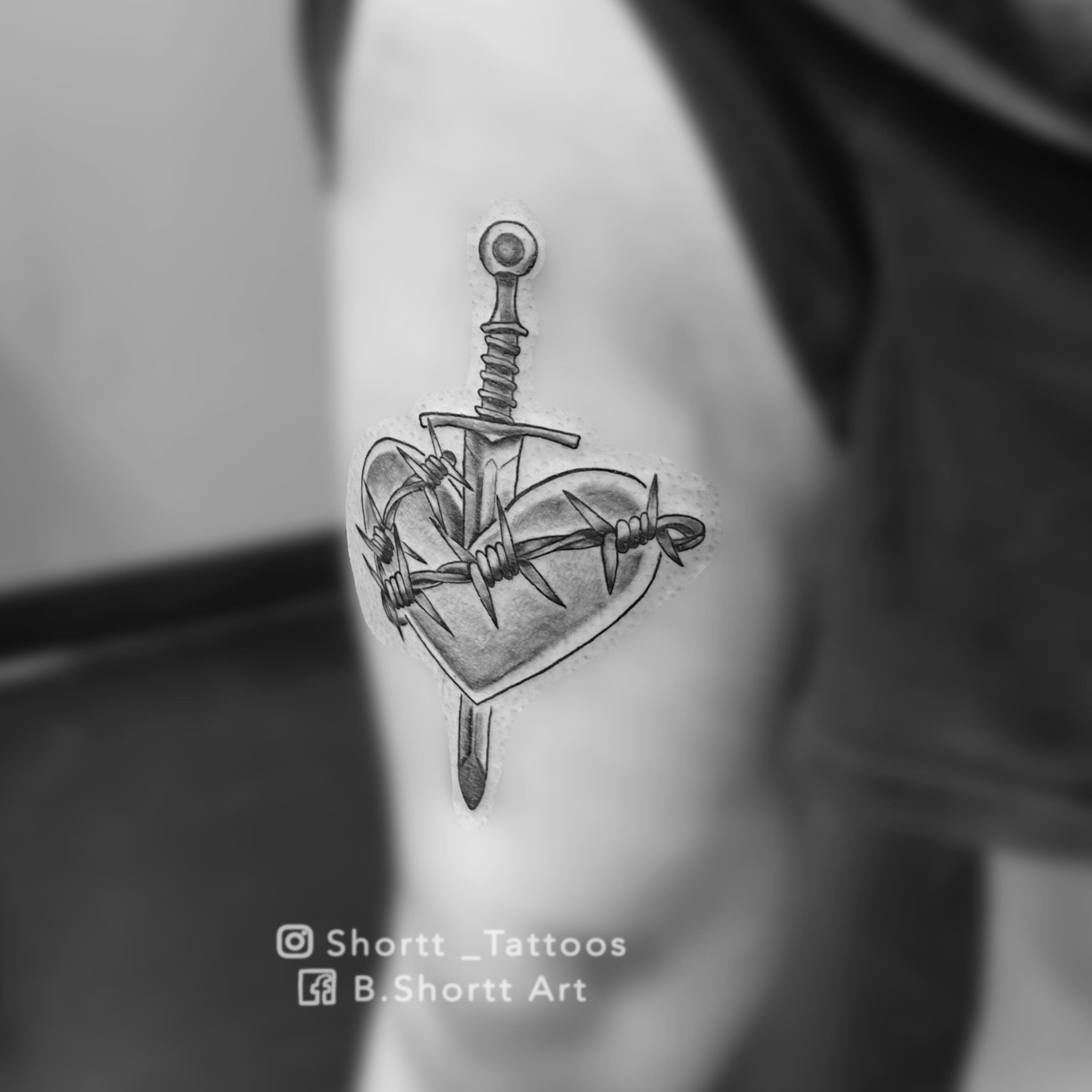 Heart with sword and barbed wire realism tattoo on the shoulder by Brie Marie