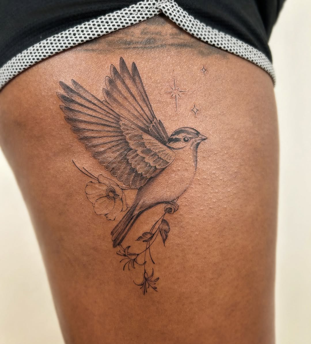 Bird with flowers fine line tattoo on the thigh by Helly March