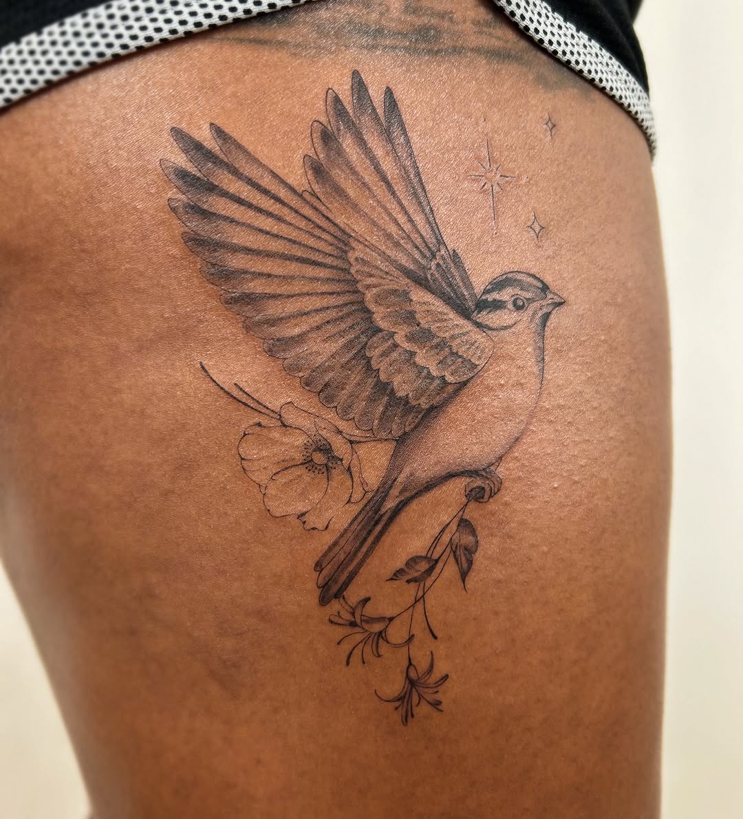 Bird with flowers fine line tattoo on the thigh by Helly March