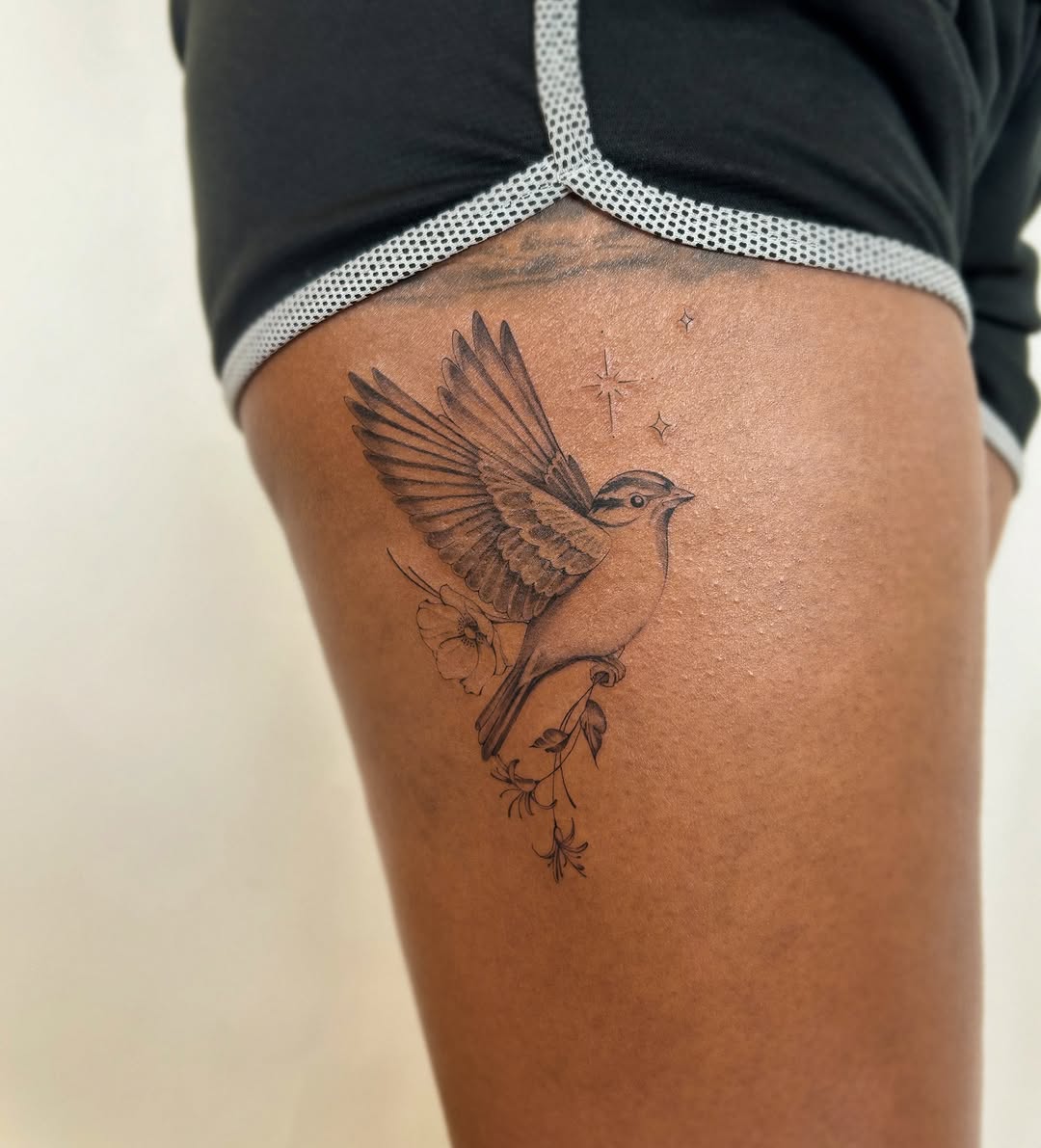 Bird and flowers fine line tattoo on the thigh by Helly March