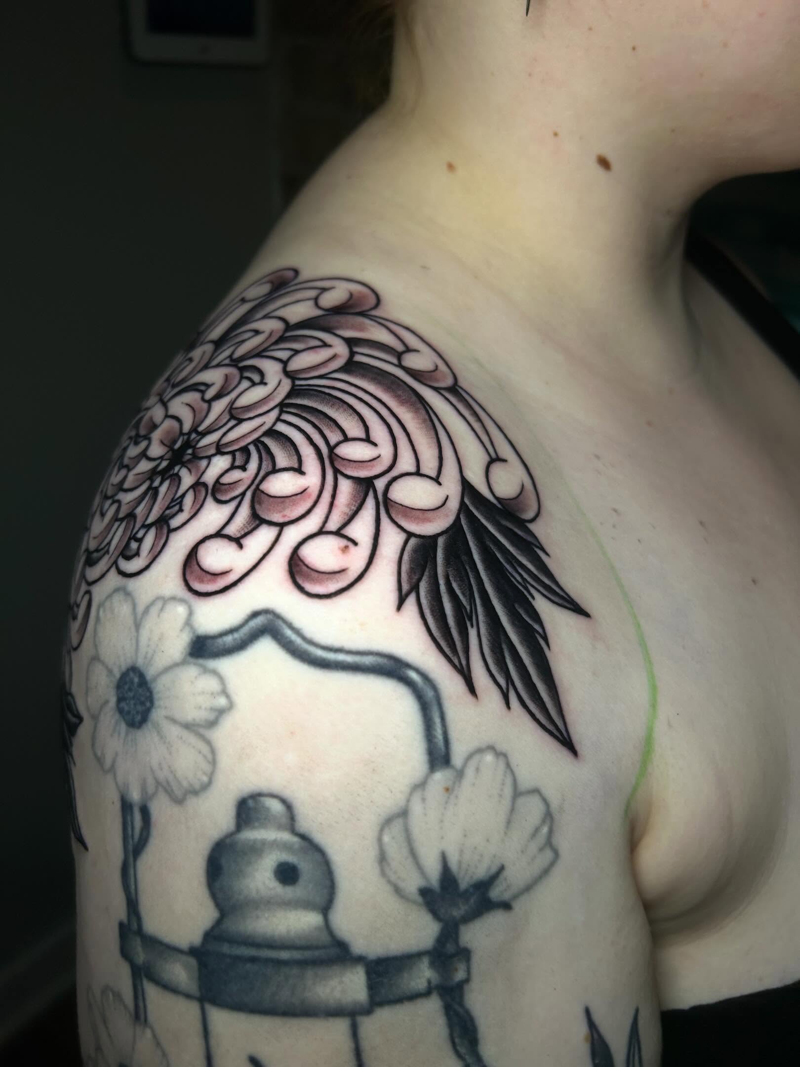 Chrysanthemum and wing black and grey tattoo on the shoulder by Alycia