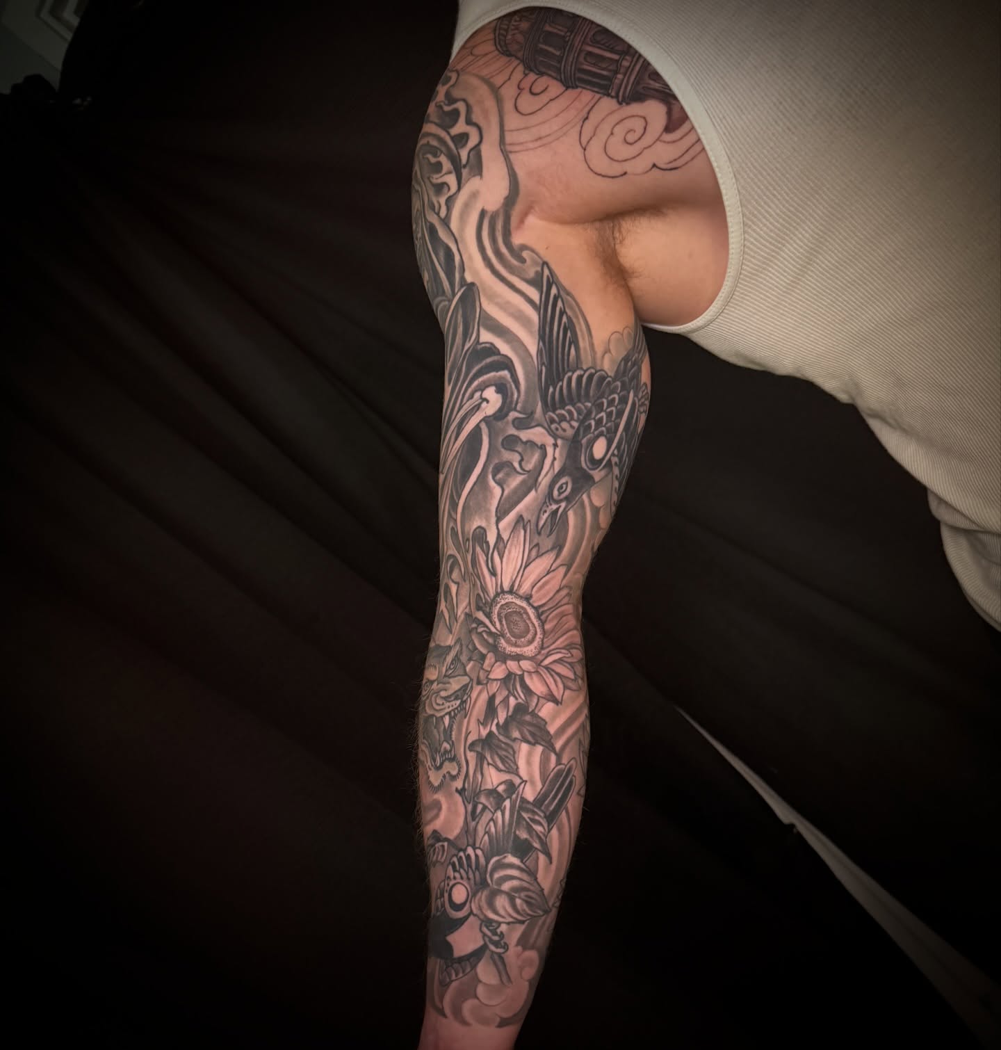 Sunflower and bird black and grey tattoo on the upper arm by Brian Hutflies