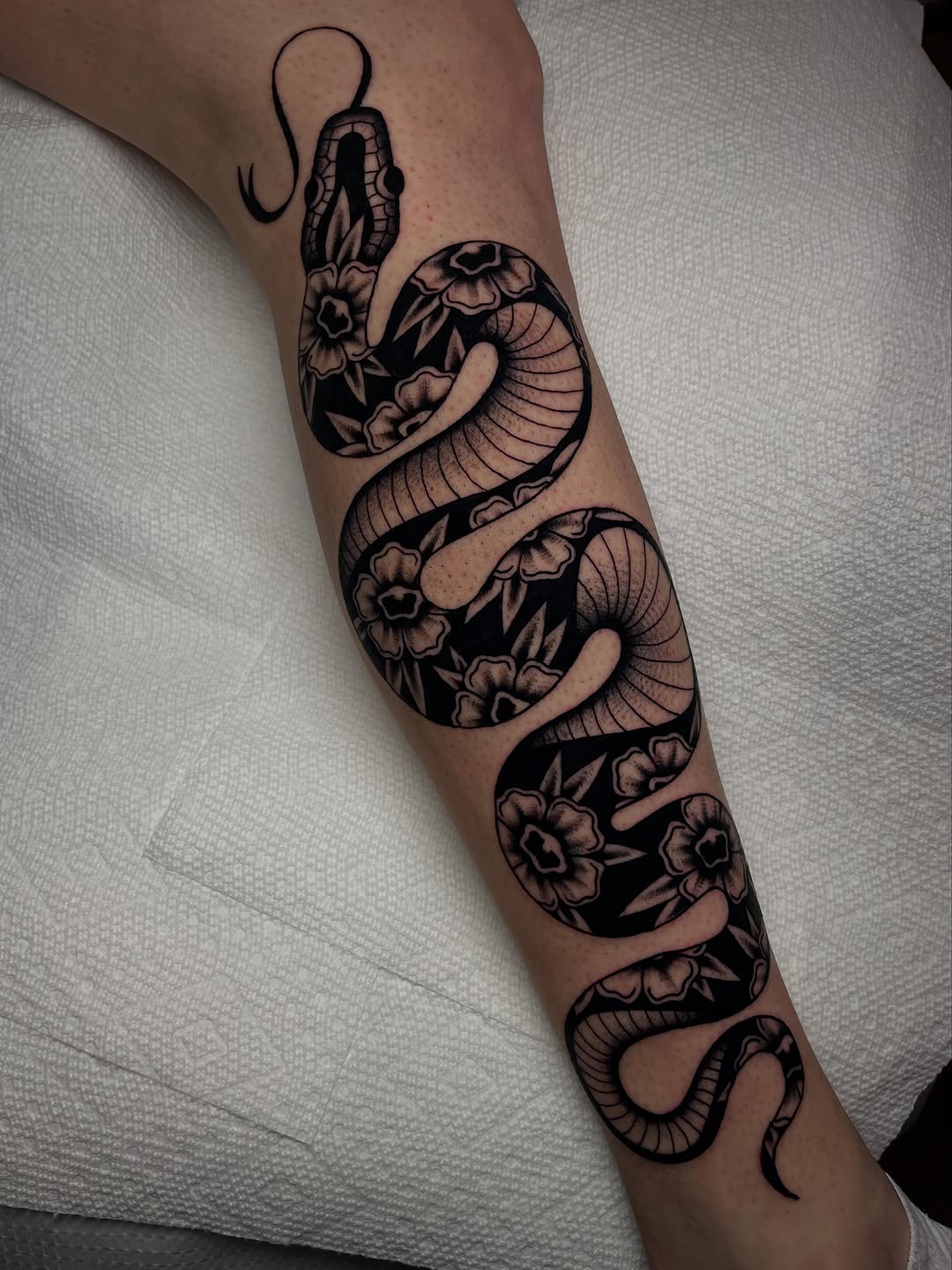 Snake and flowers American traditional tattoo on the forearm by Marqui Watling