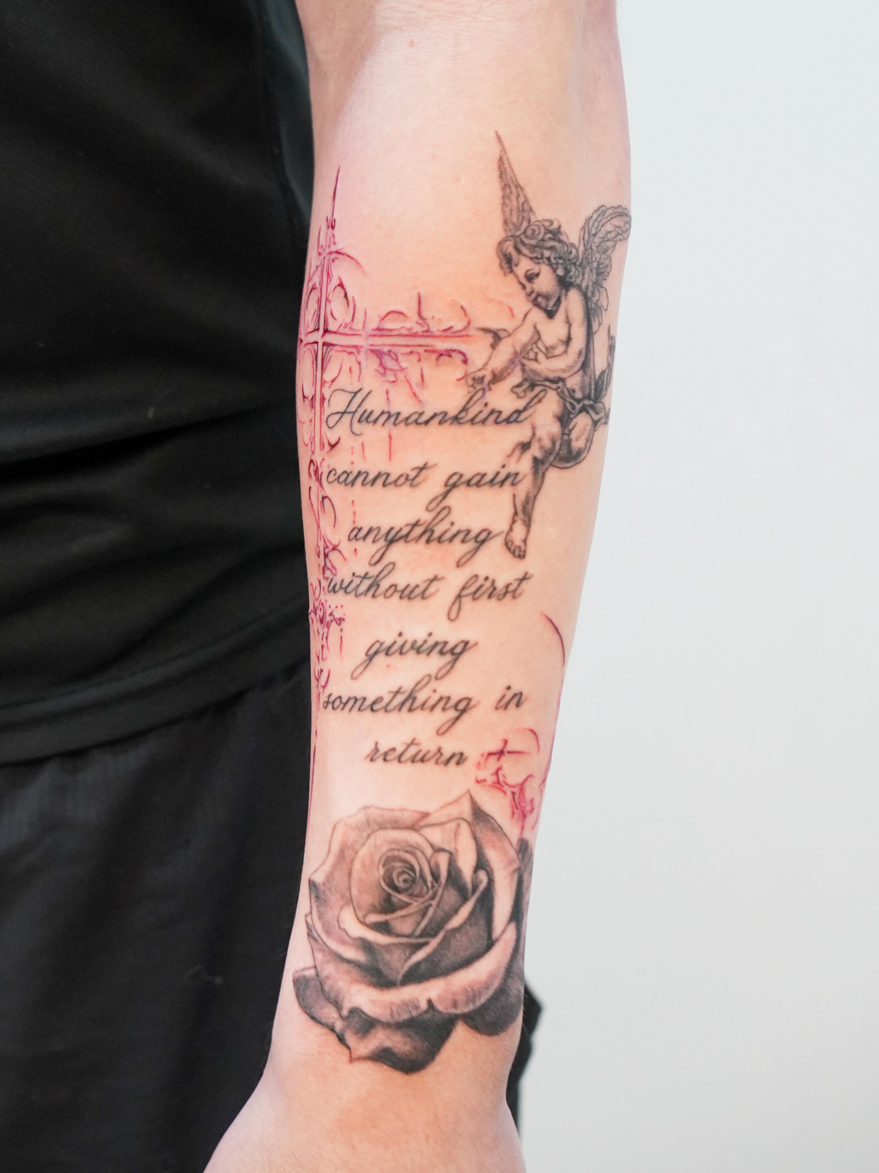 Cherub and rose black and grey tattoo on the forearm by Skylar