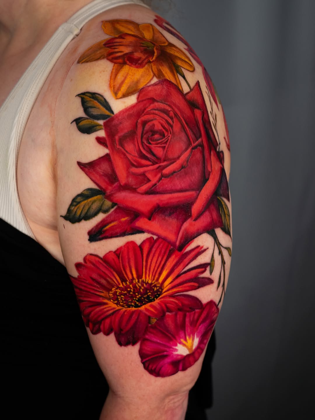 Rose and other flowers neo-traditional tattoo on the upper arm by Nate