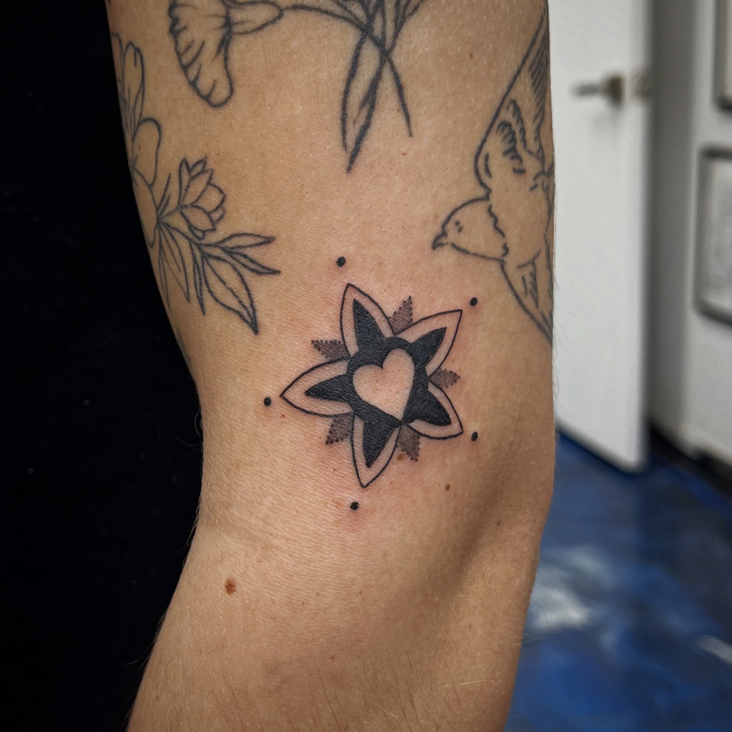 Heart within star dotwork tattoo on the forearm by Sid
