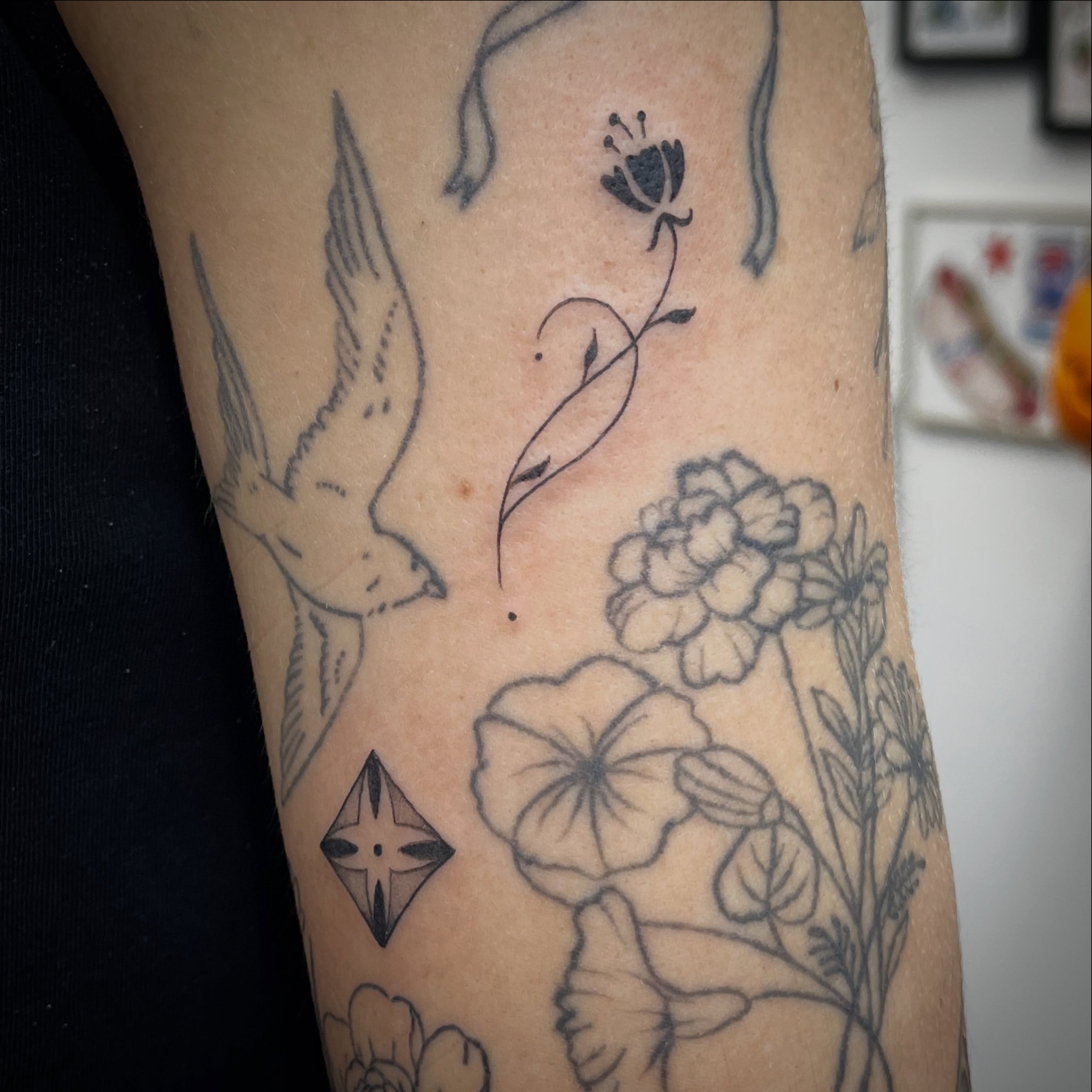 Bird and flowers black and grey tattoo on the forearm by Sid