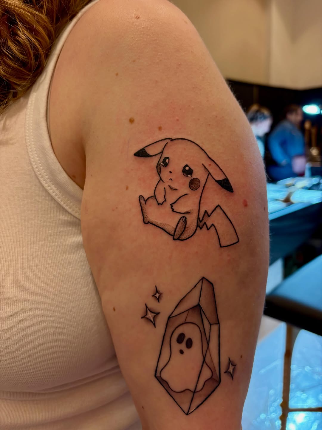 Pikachu and ghost in crystal new school tattoo on the upper arm by Krista Reid