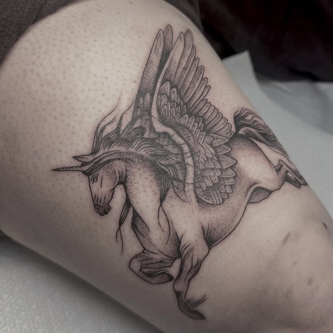 Winged unicorn fine line tattoo on the thigh by Lia Massari