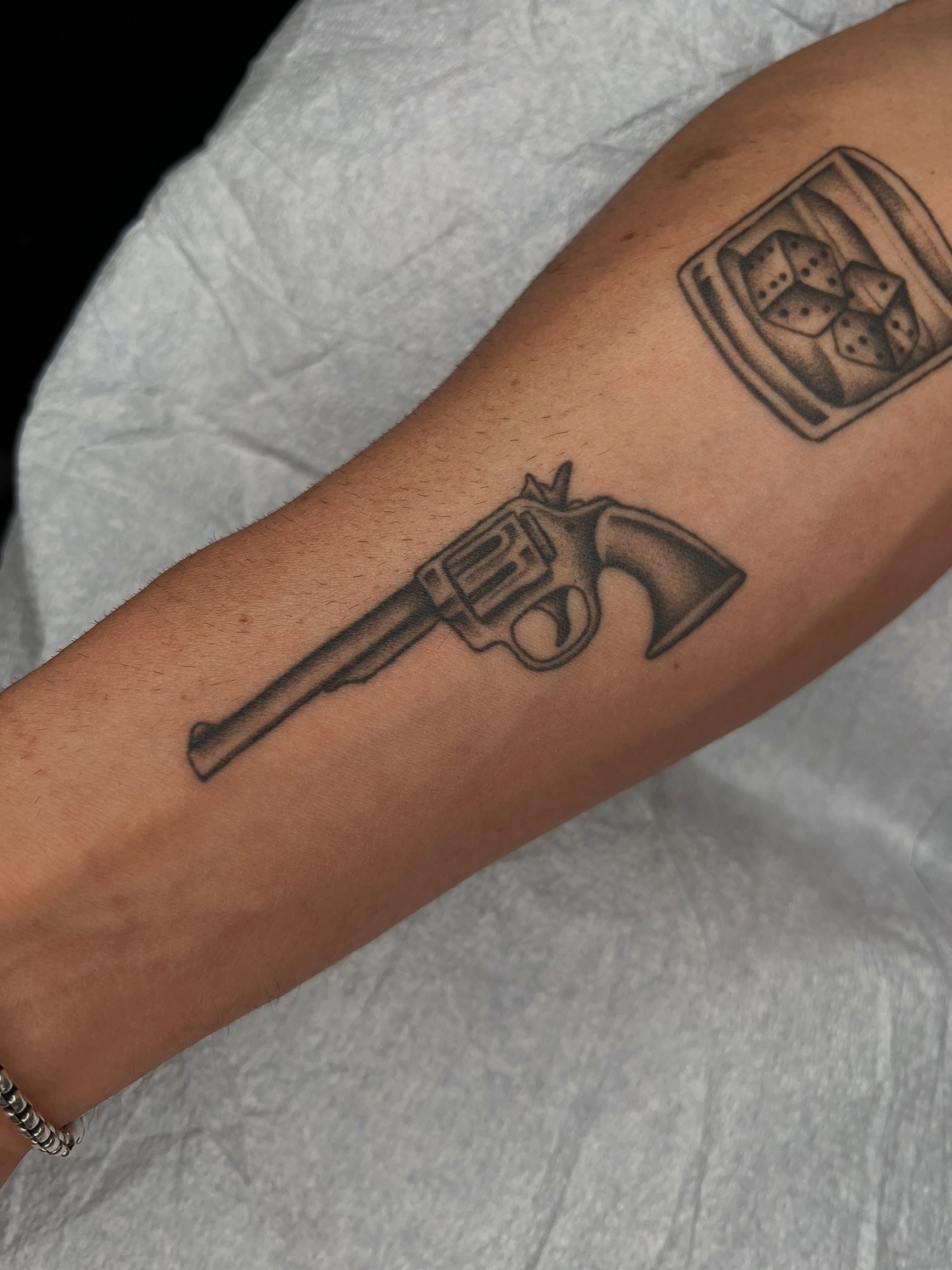 Revolver black and grey tattoo on the forearm by Patrick Elijah