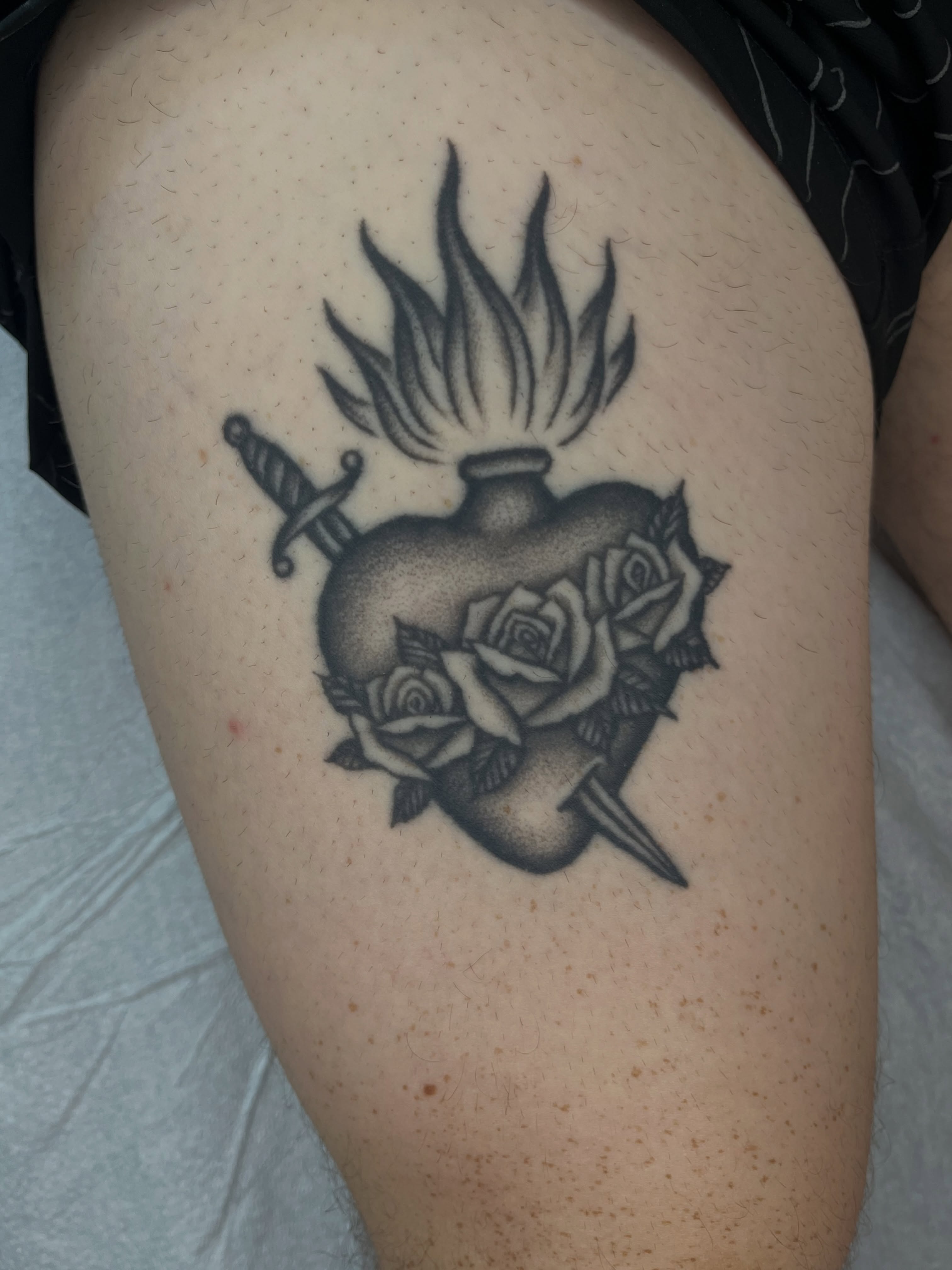 Burning heart with roses and dagger dotwork tattoo on the thigh by Patrick Elijah