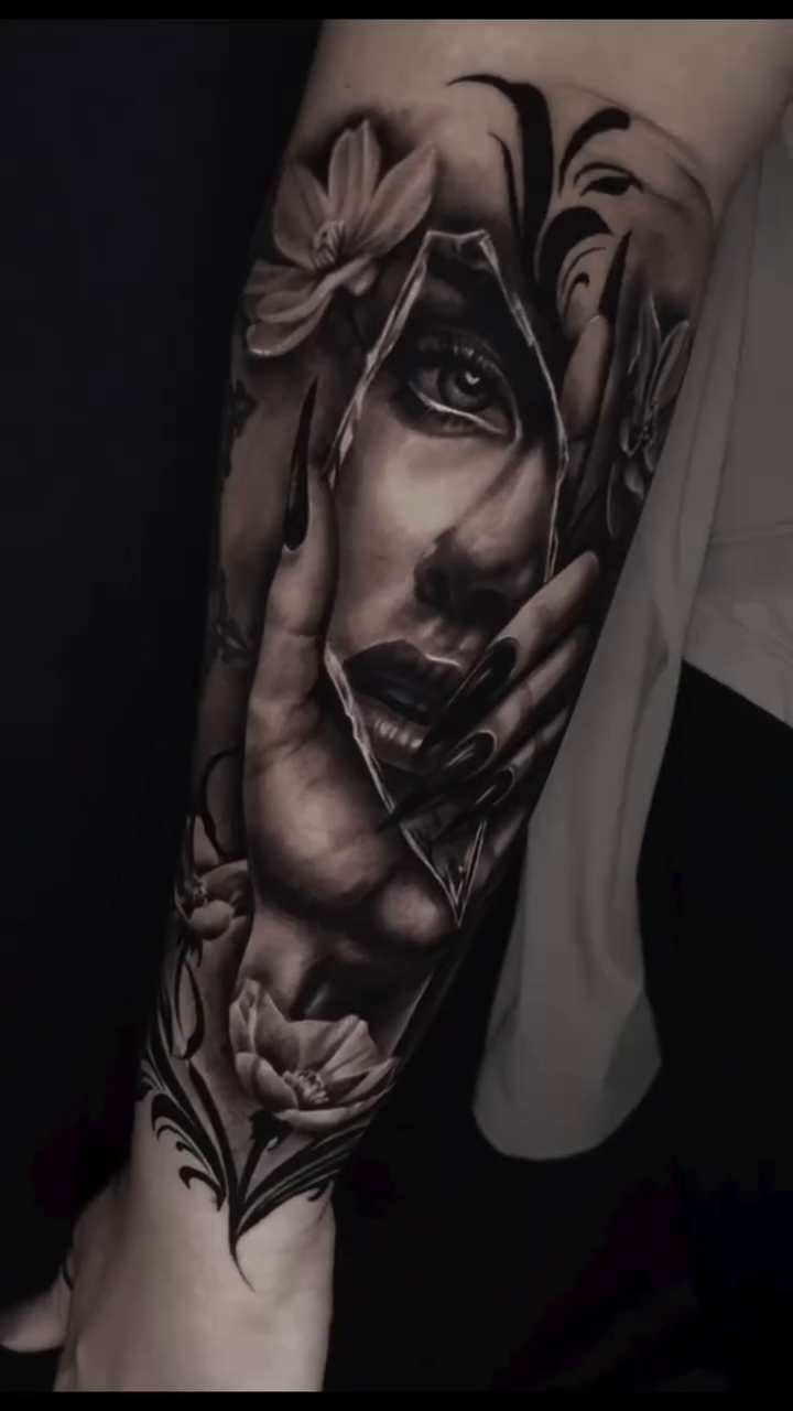 Portrait of a woman with flowers realism tattoo on the upper arm by Aaron Watson