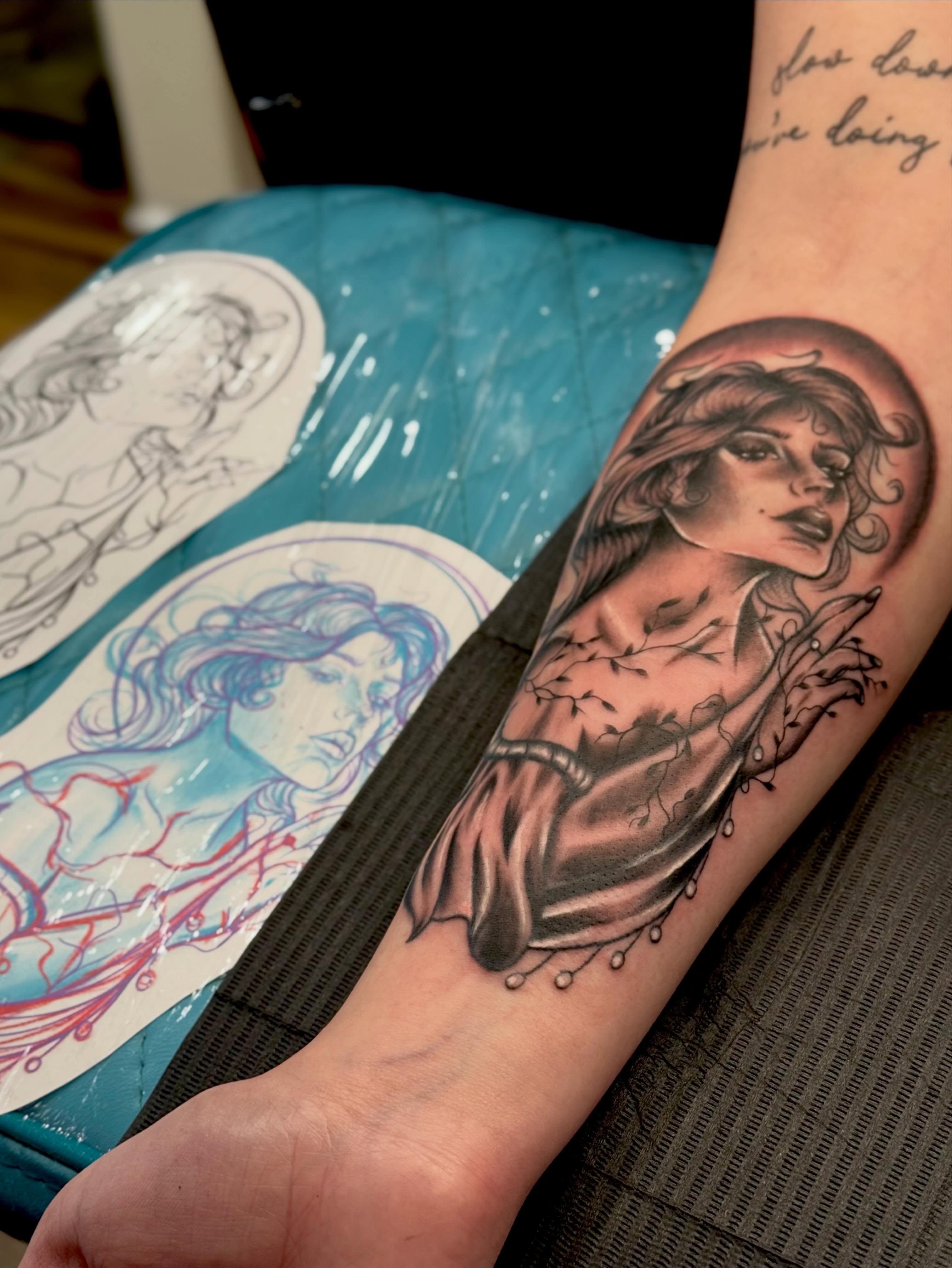 Woman with curly hair black and grey tattoo on the forearm by Serenity Mullins