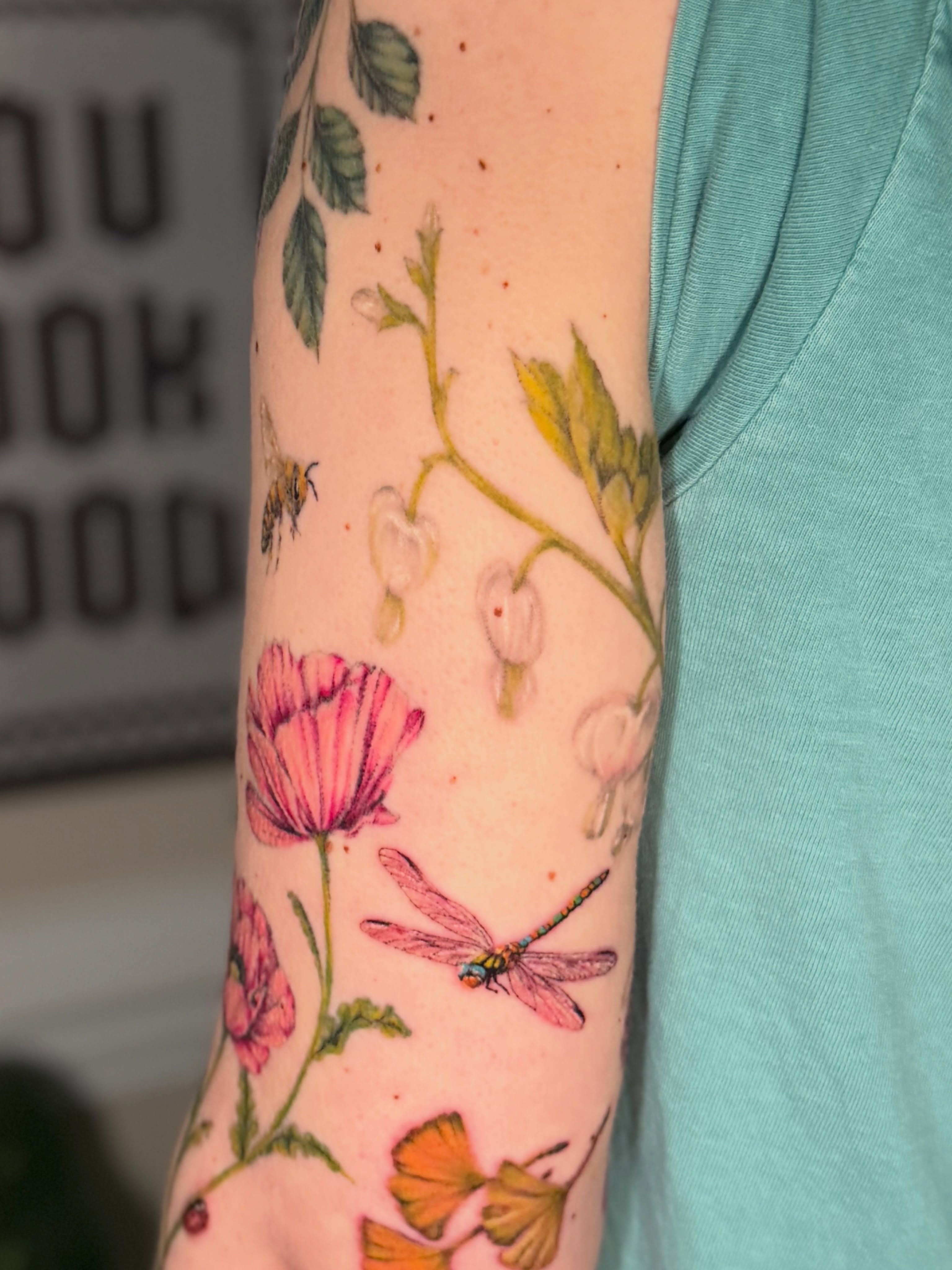 Flowers and dragonfly watercolor tattoo on the forearm by Chiah