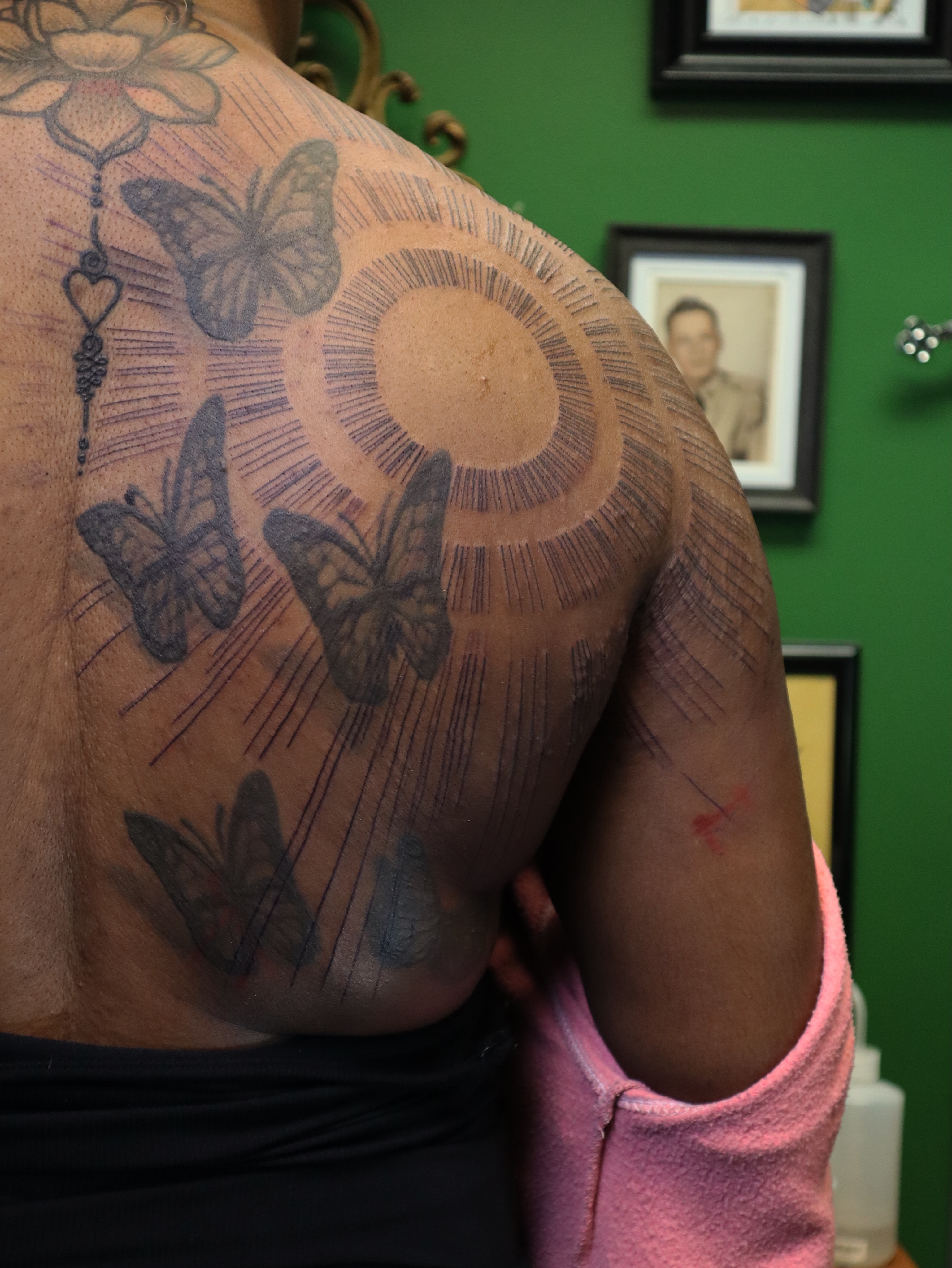 Butterflies and sunburst black and grey tattoo on the shoulder by Joe Hall