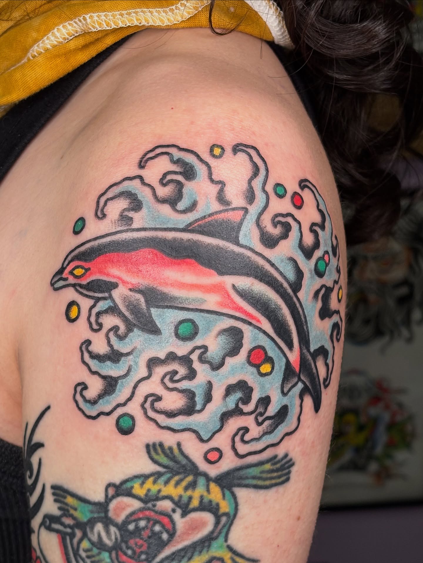 Dolphin and wave American traditional tattoo on the shoulder by Andrew Silva