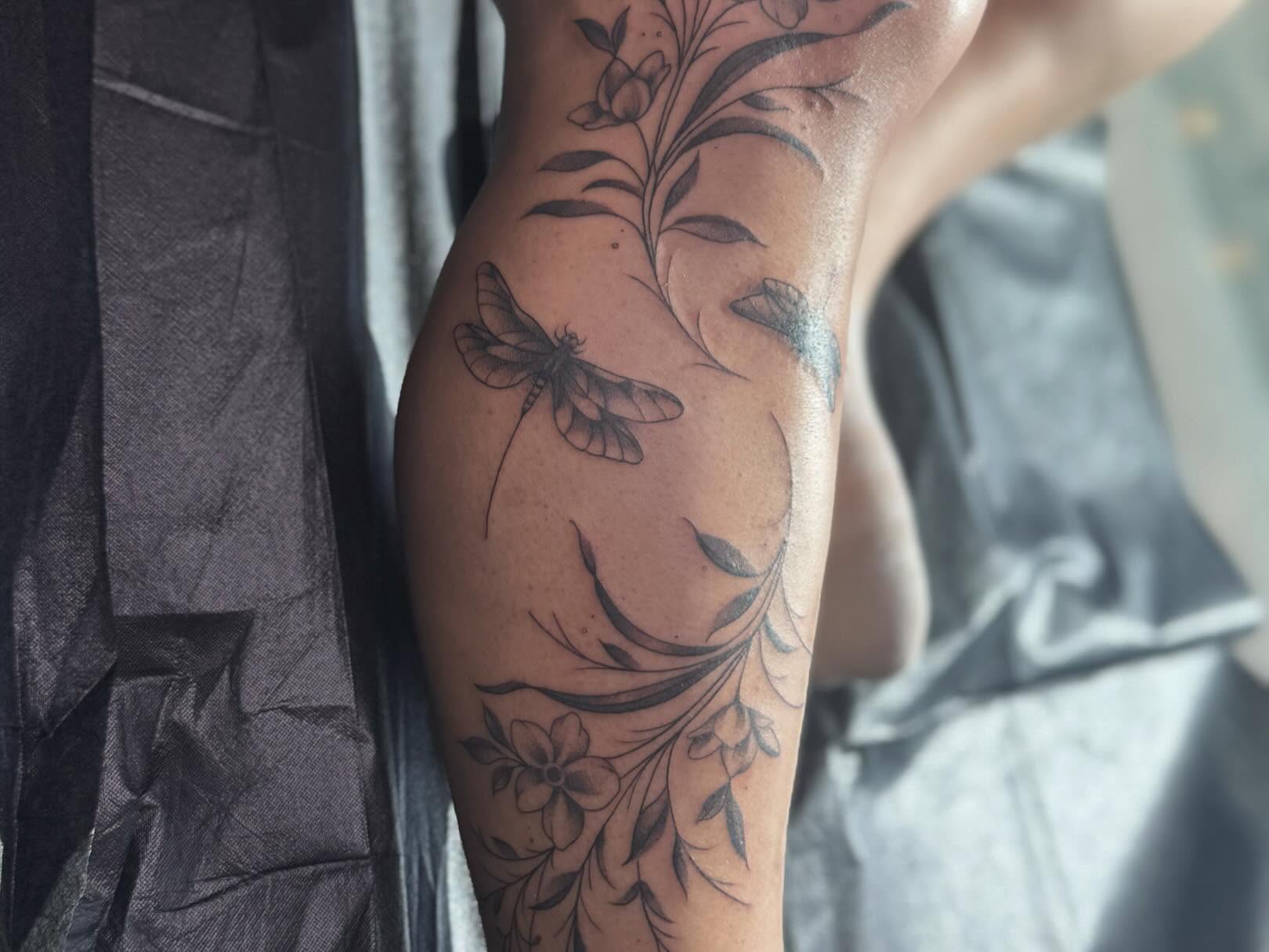 Dragonfly and floral black and grey tattoo on the upper arm by Tattoo, San Diego, California