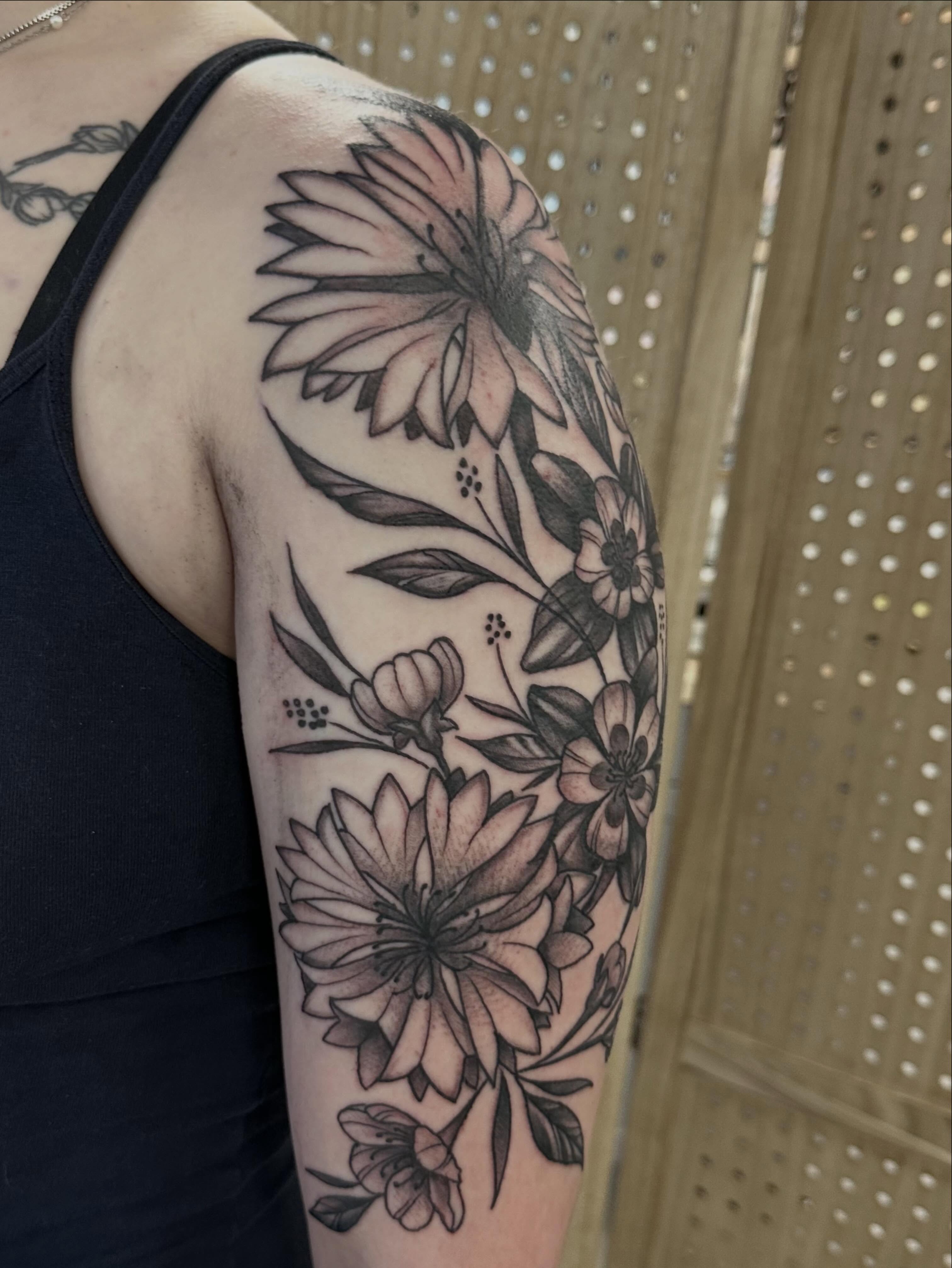 Floral bouquet black and grey tattoo on the upper arm by Vincent Merys