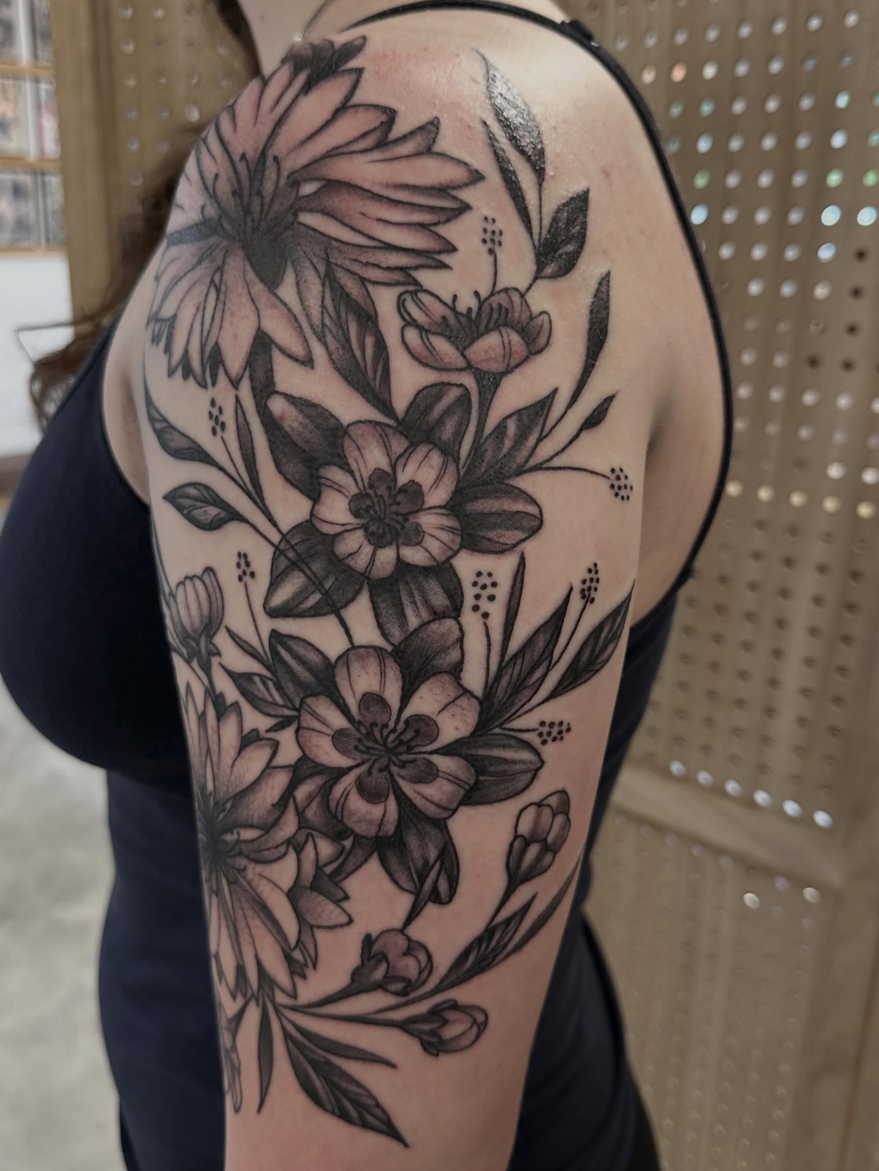 Floral bouquet black and grey tattoo on the upper arm by Vincent Merys
