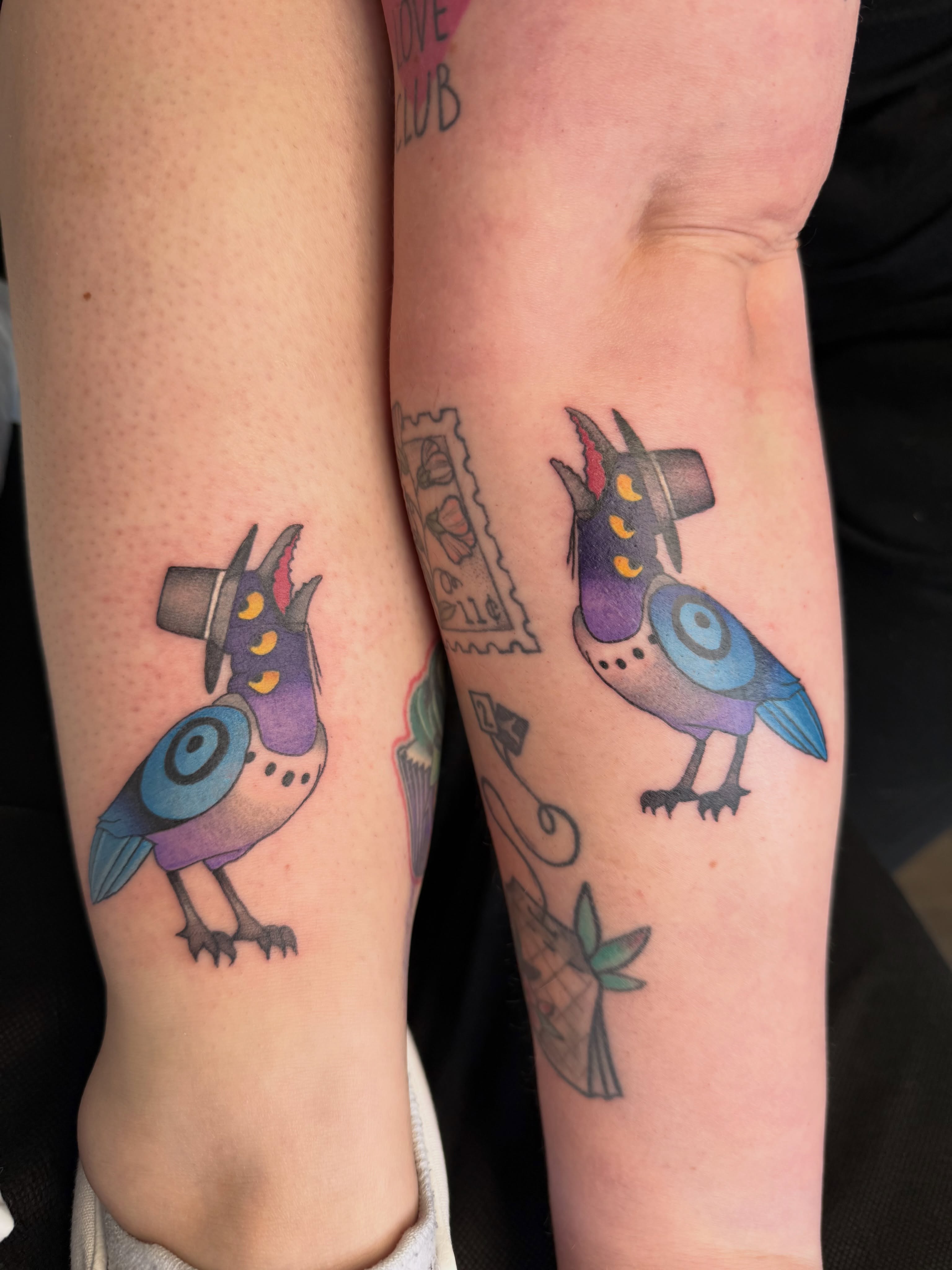 Bird wearing hat new school tattoo on the forearm by Alexx Colombo