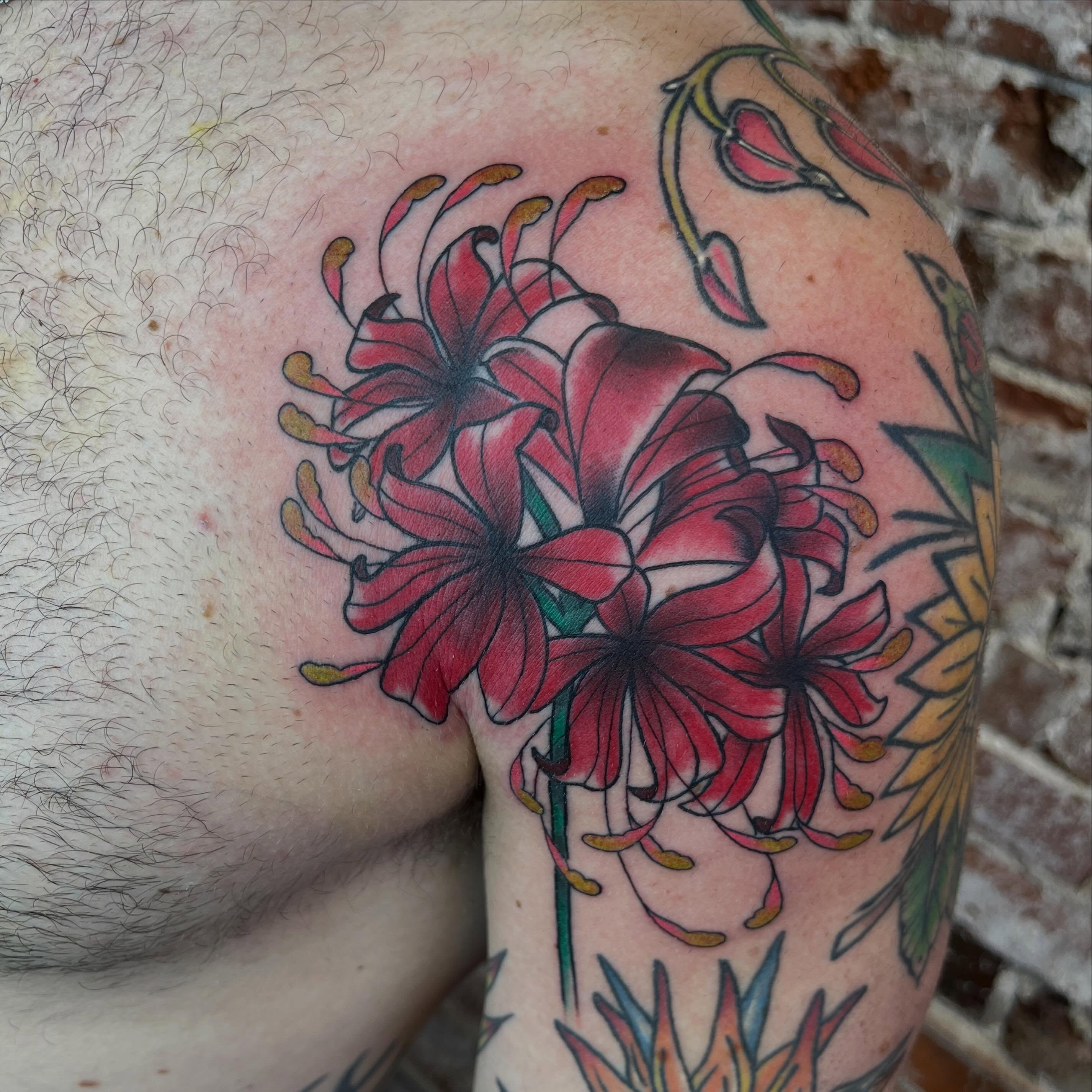 Red lilies American traditional tattoo on the shoulder by Evan Voelker
