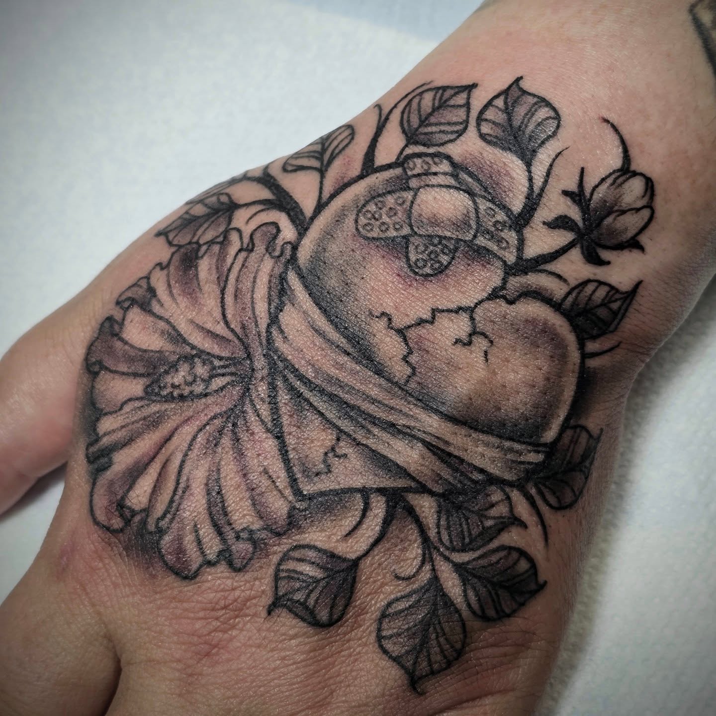 Heart with flowers black and grey tattoo on the hand by bonnie